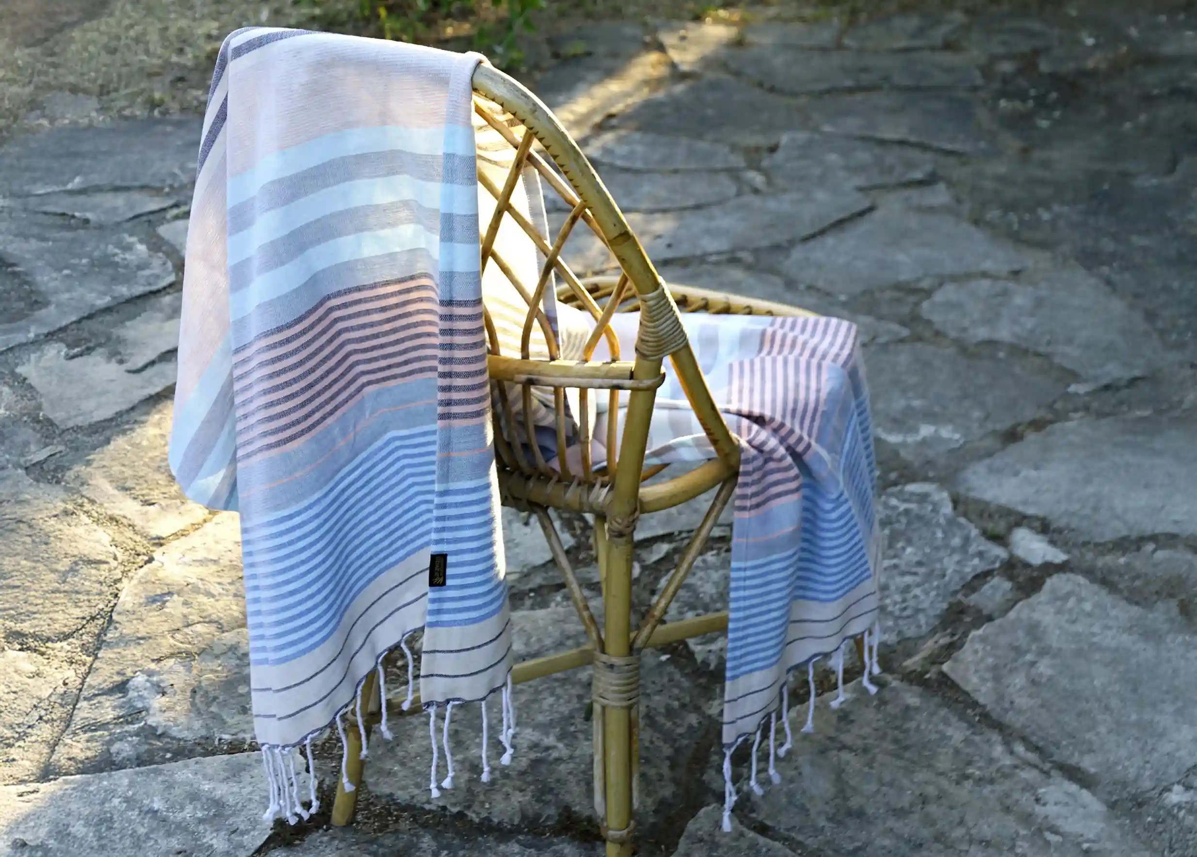 Waves-coloured fouta in cotton on a chair, fringes falling to one side