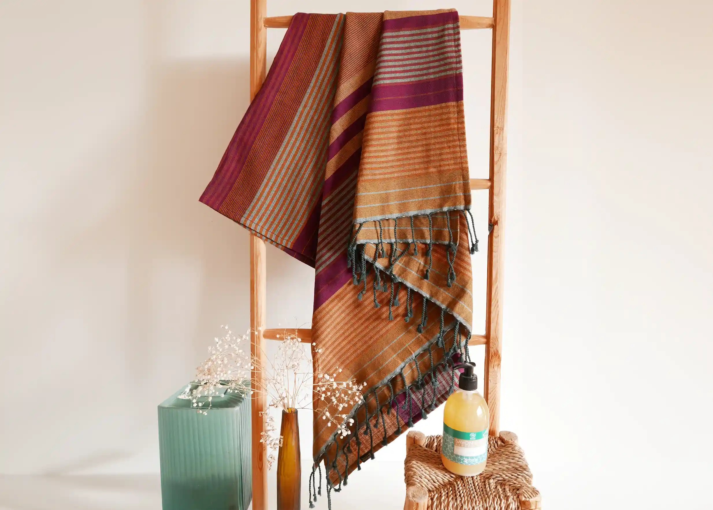 Arabesk-coloured fouta in organic cotton hanging from a wooden ladder, white wall