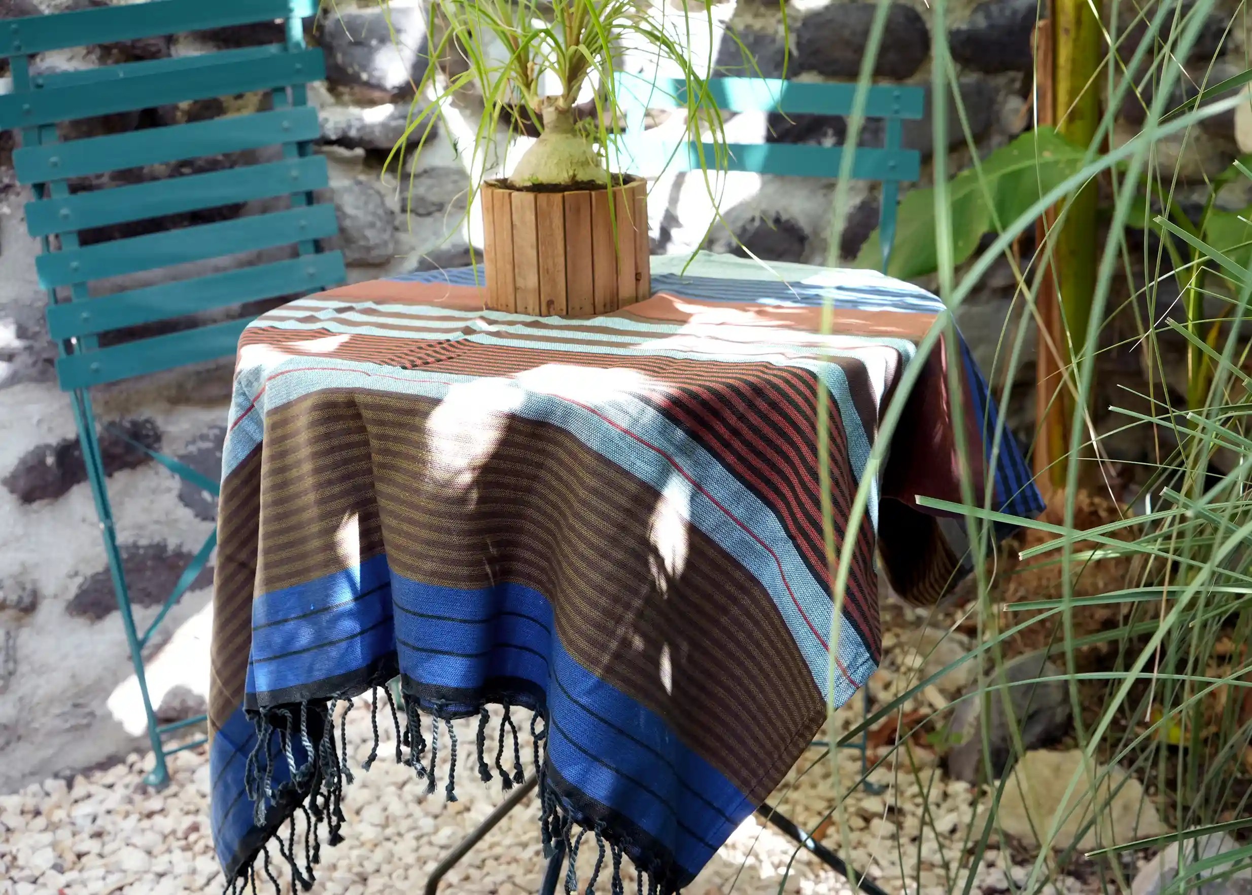 Fouta artisanale en coton bio, coloris Céleste, étendue en extérieur sur une table, une plante au-dessus