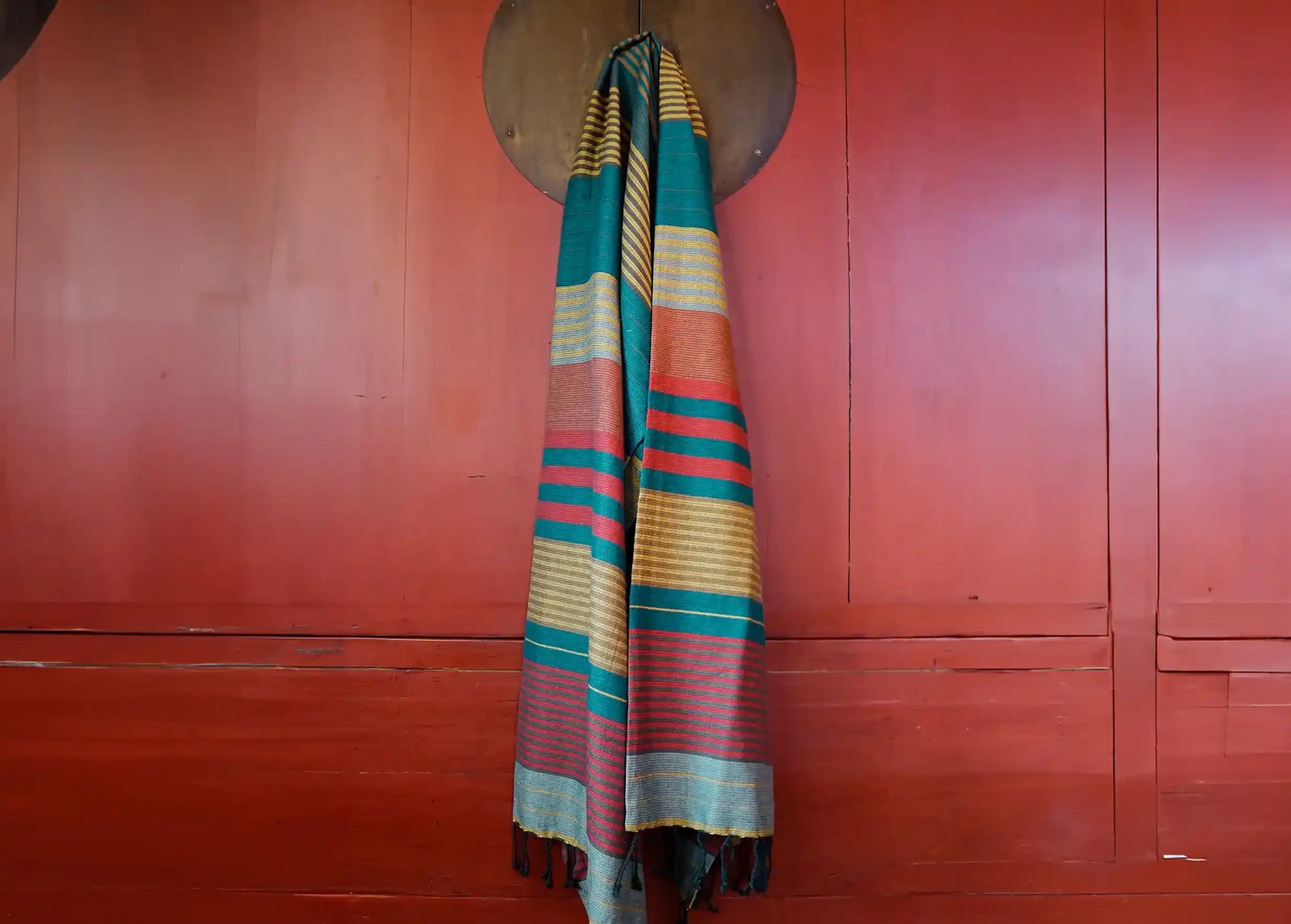 Redblue-coloured flat-woven organic cotton fouta, hung on a red wall
