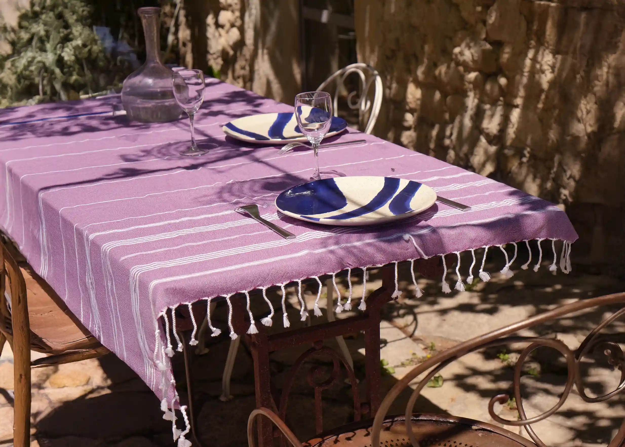 Fouta couleur bordeaux aux rayures blanches recouvrant toute une table dressée, en extérieur Fouta couleur bordeaux aux rayures blanches recouvrant toute une table dressée, en extérieur