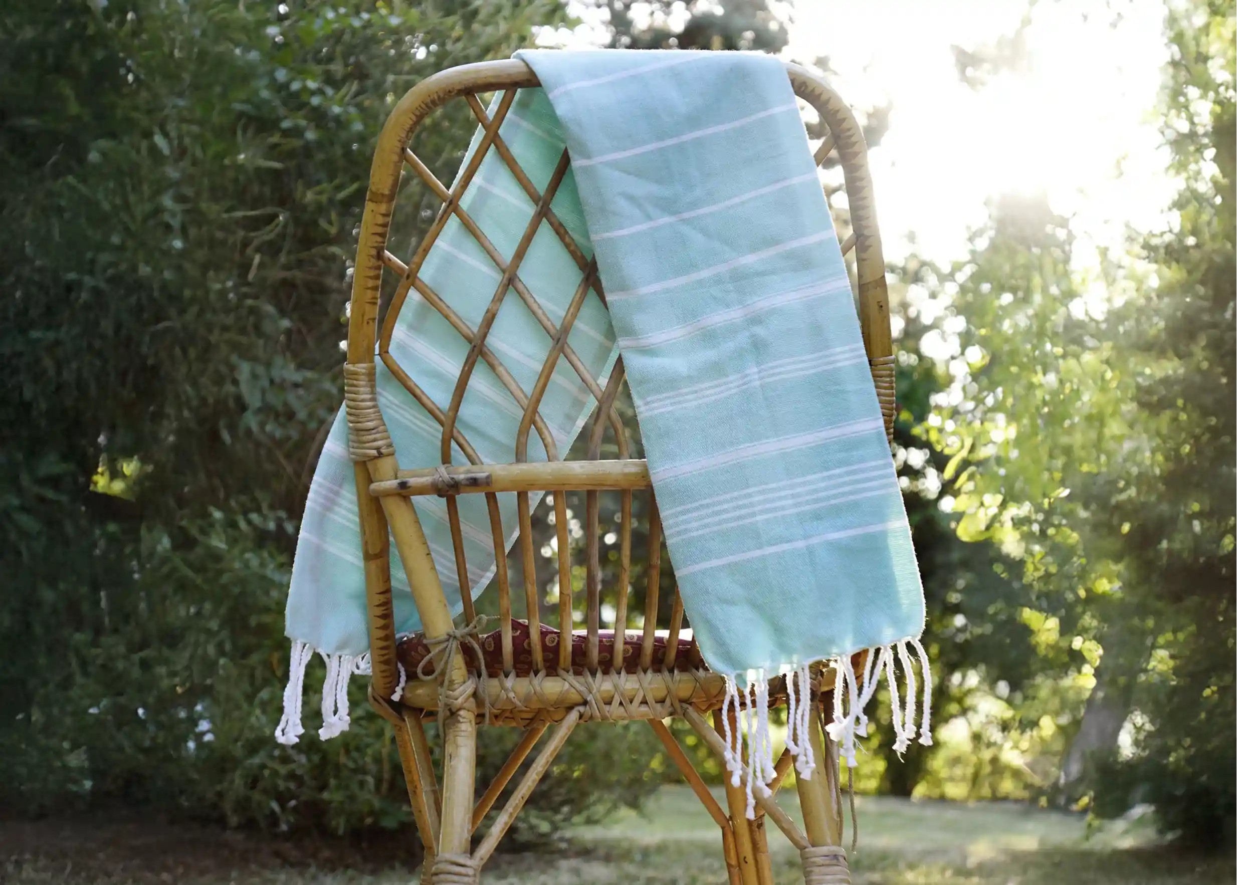 Fouta en coton bio coloris menthe, issue de la collection Hammam, sur une chaise dans un décor extérieur Fouta en coton bio coloris menthe, issue de la collection Hammam, sur une chaise dans un décor extérieur