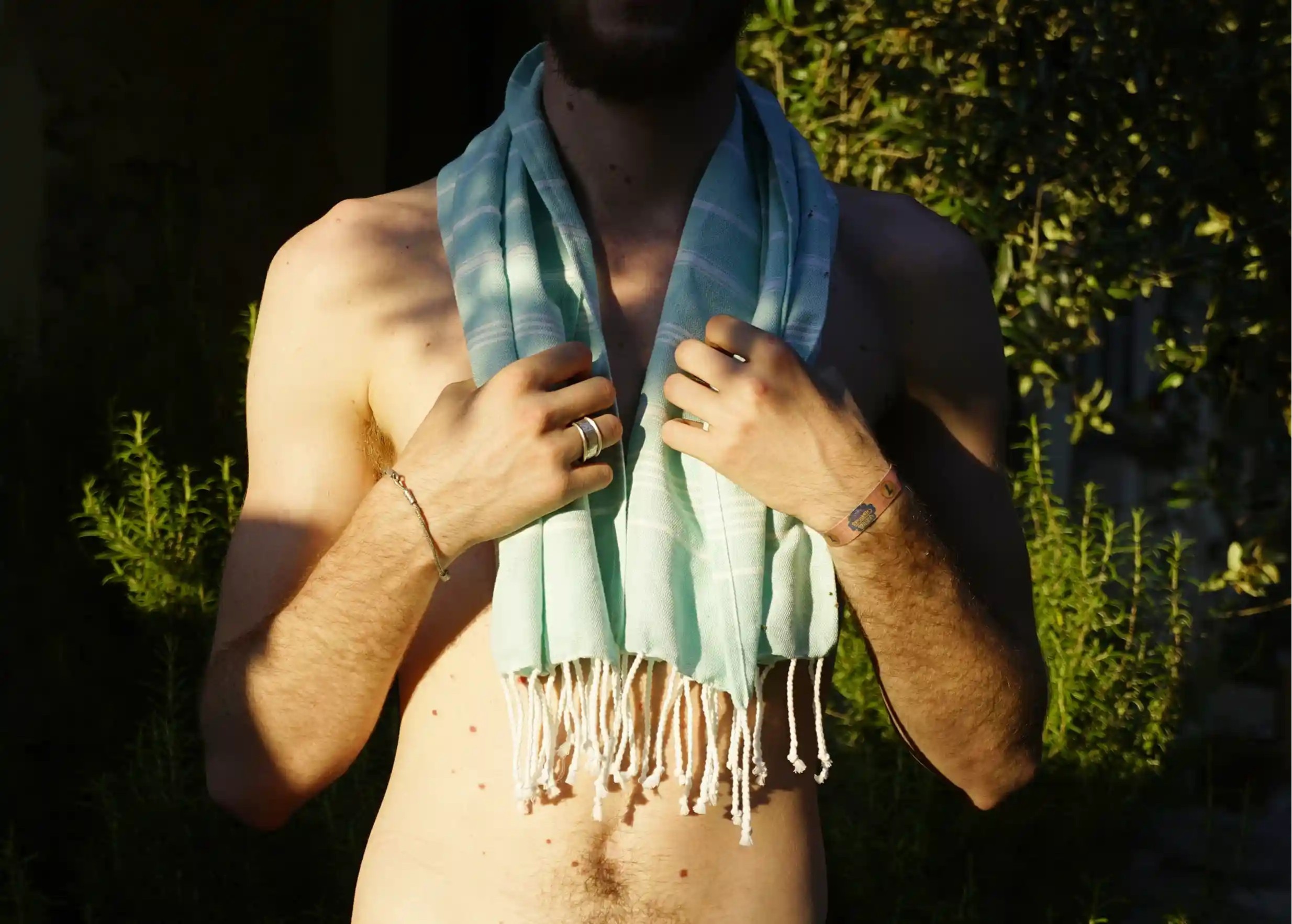 Fouta en coton bio, aux franges blanches et tissée à la main, portée autour du cou par un homme Fouta en coton bio, aux franges blanches et tissée à la main, portée autour du cou par un homme