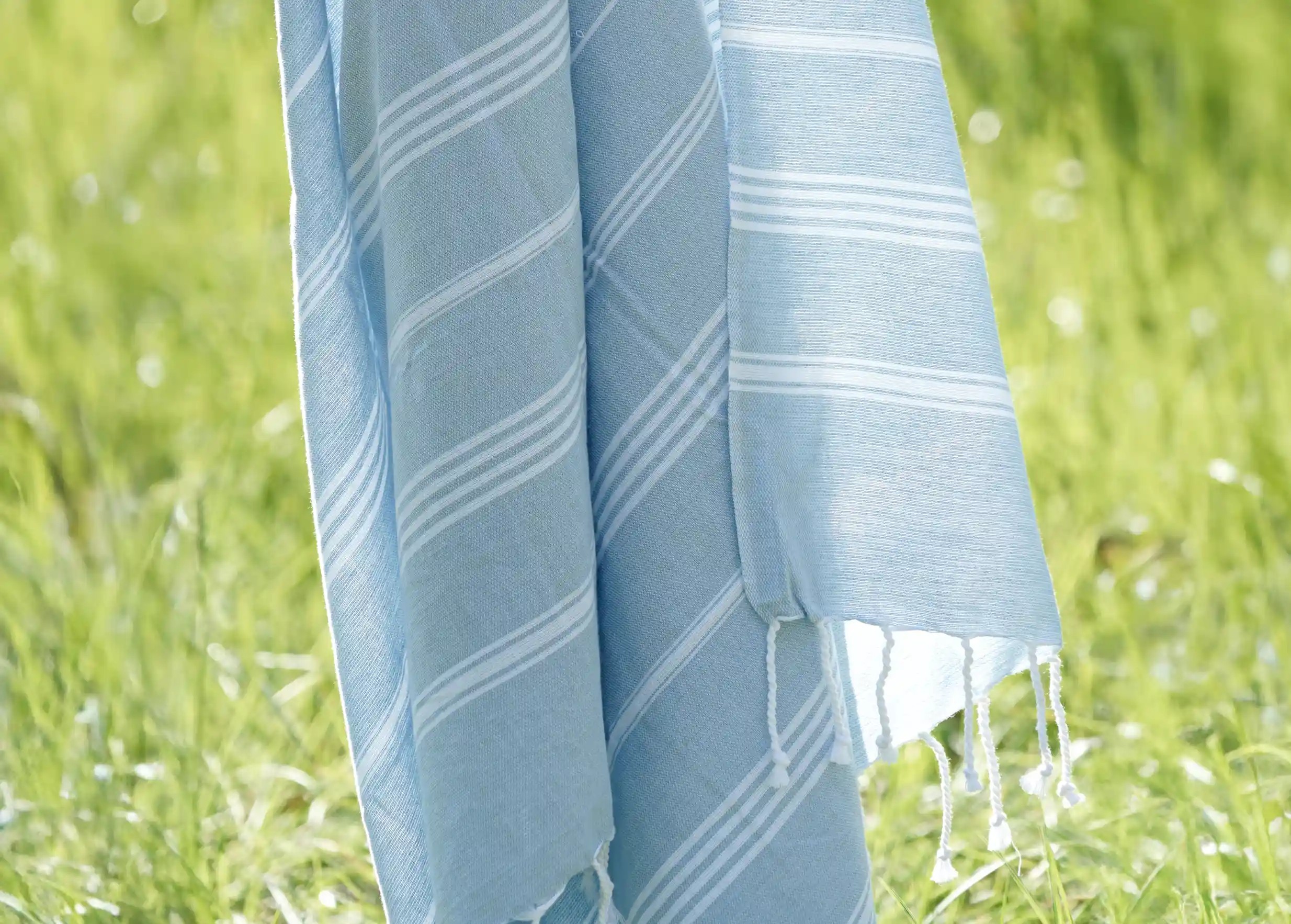 Fouta en coton bio coloris nuage, suspendue en plein air au-dessus d'une pelouse Fouta en coton bio coloris nuage, suspendue en plein air au-dessus d'une pelouse
