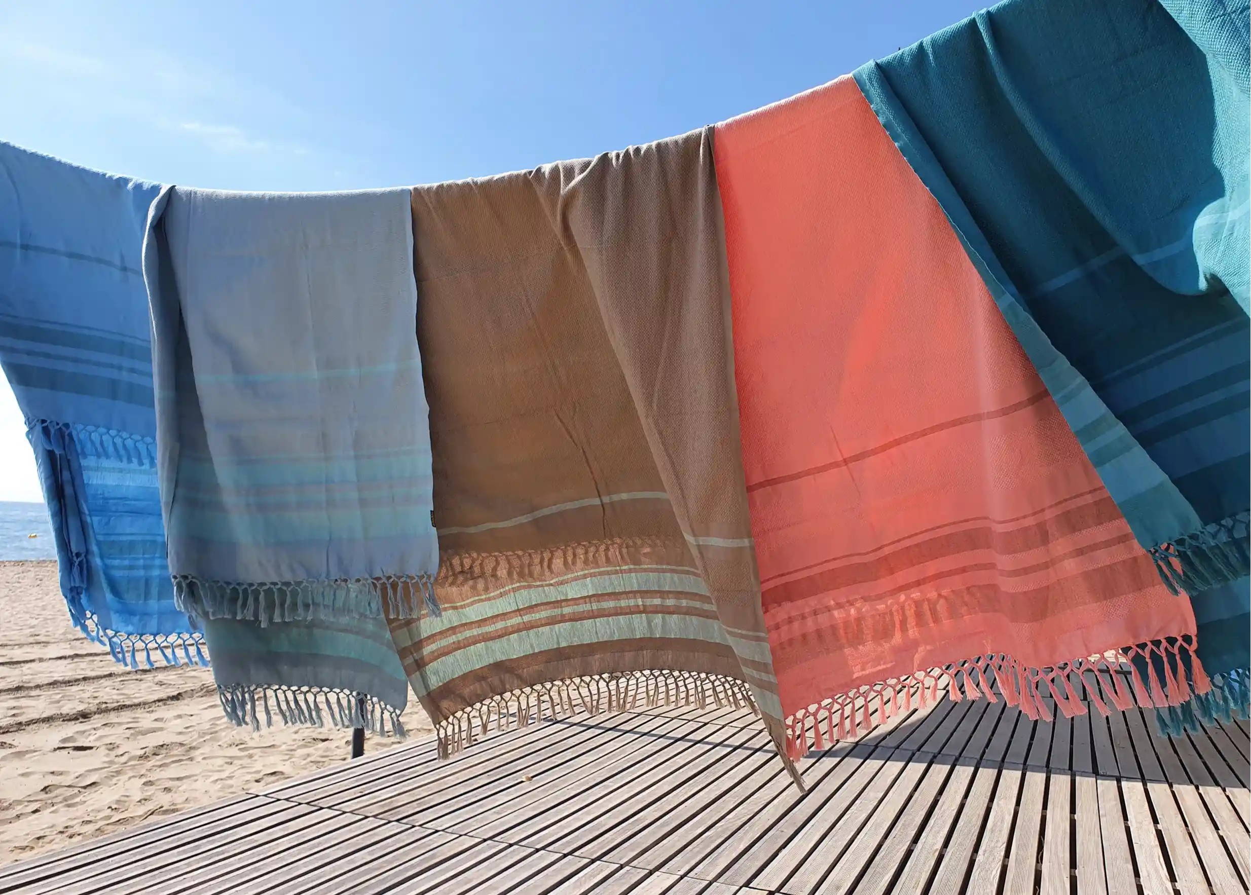 Collection of Garden foutas in organic cotton, honeycomb weave, hanging near a beach, clear sky