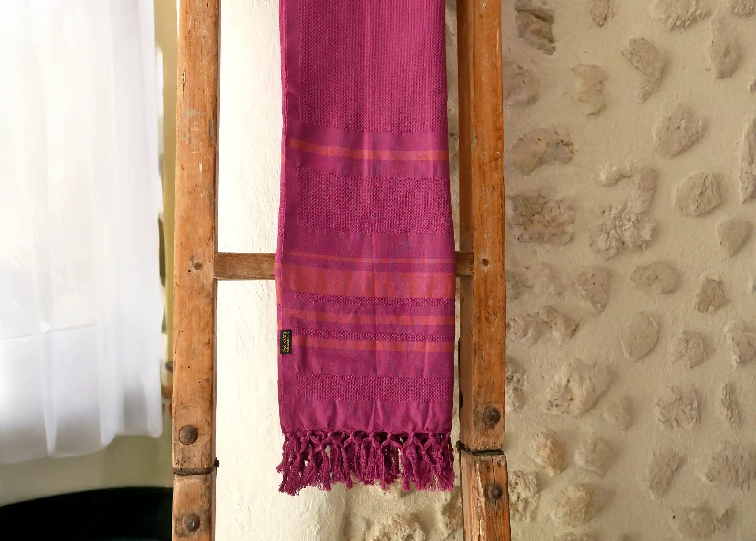 Fouta en coton biologique Garden au tissage nid d'abeille contre une échelle en bois, mur de pierre