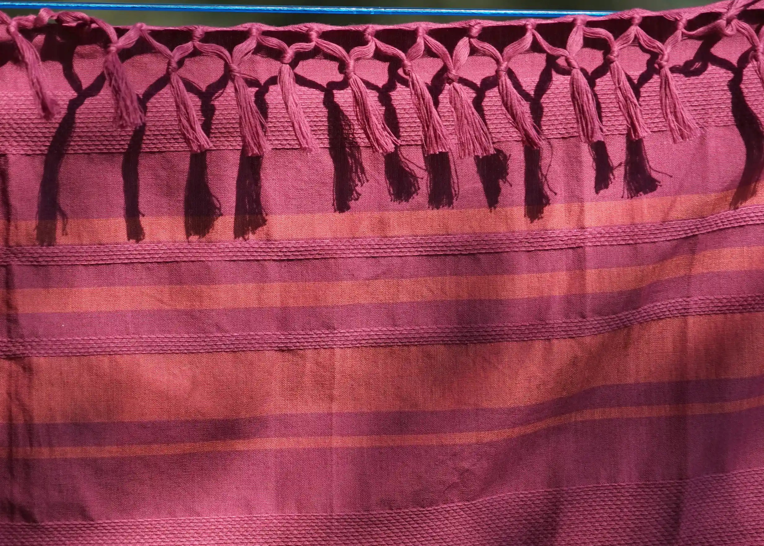 Zoom sur fouta en coton bio coloris Fushia, ses rayures orangées et son tissage en nid d'abeille