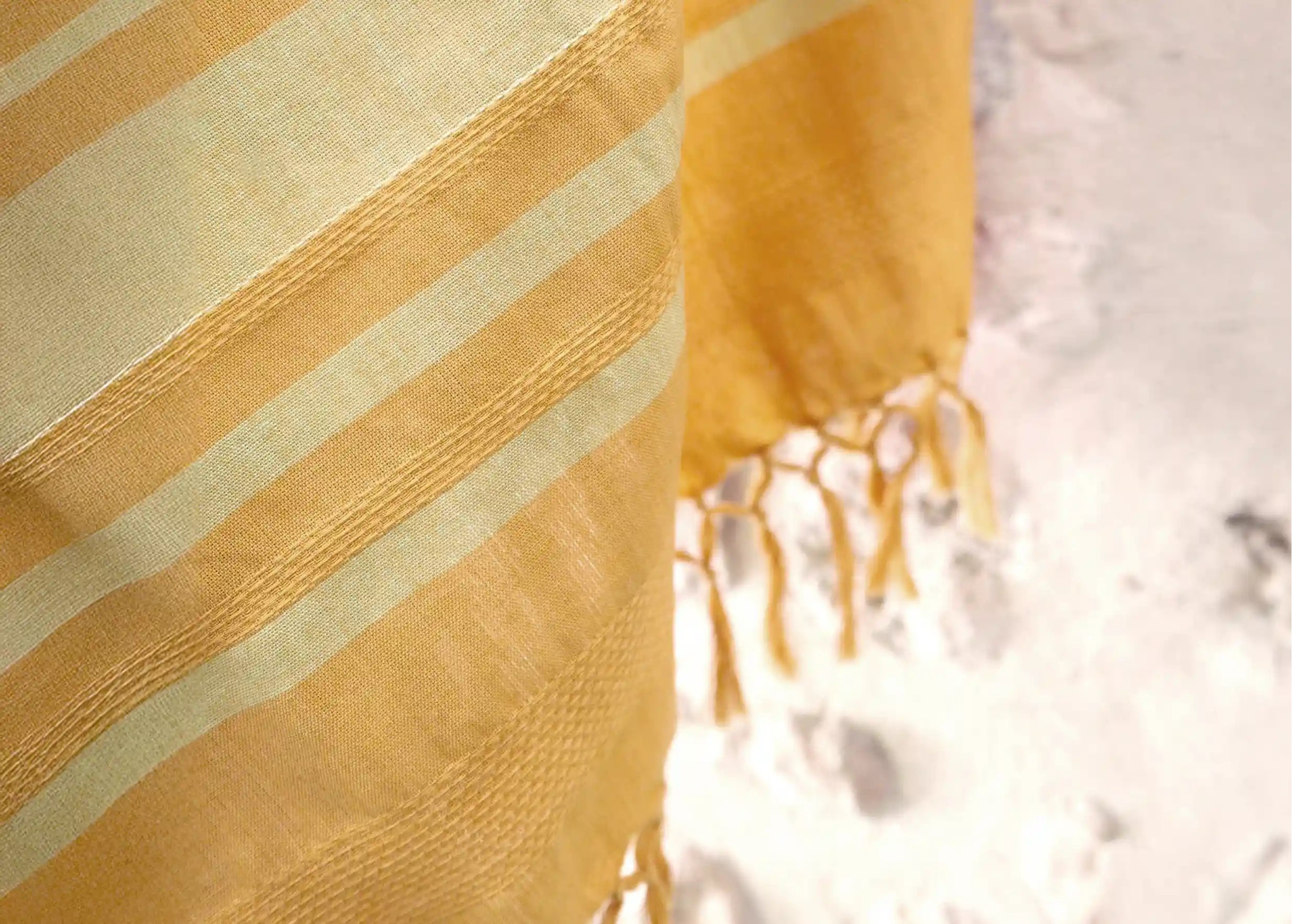 Gros plan sur fouta en coton bio Sunflower de la collection Garden,  contre un mur blanc