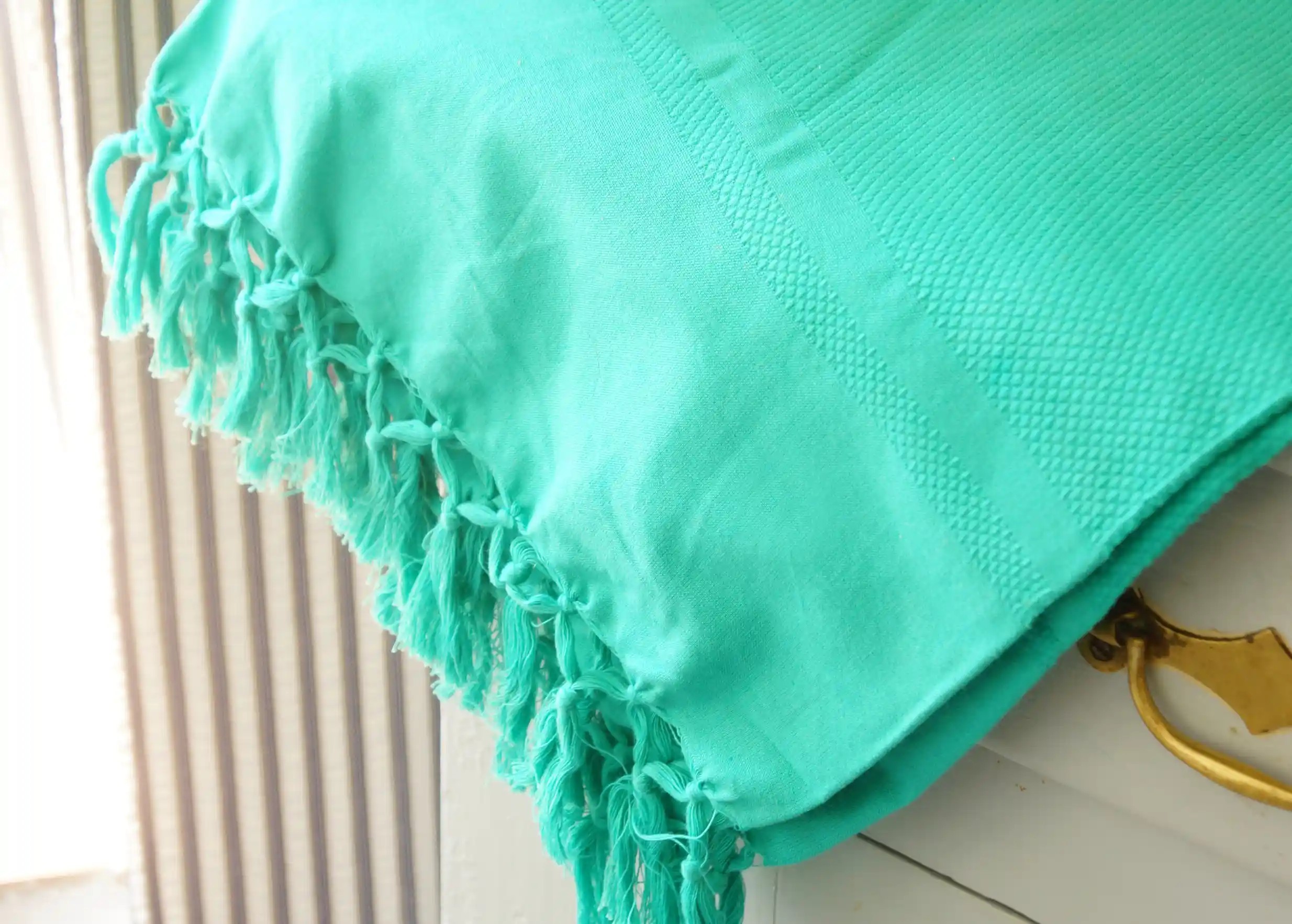 Fouta en coton bio coloris Lagon bleu, vue partiellement, plan zoomé sur ses franges nouées de manière artisanale