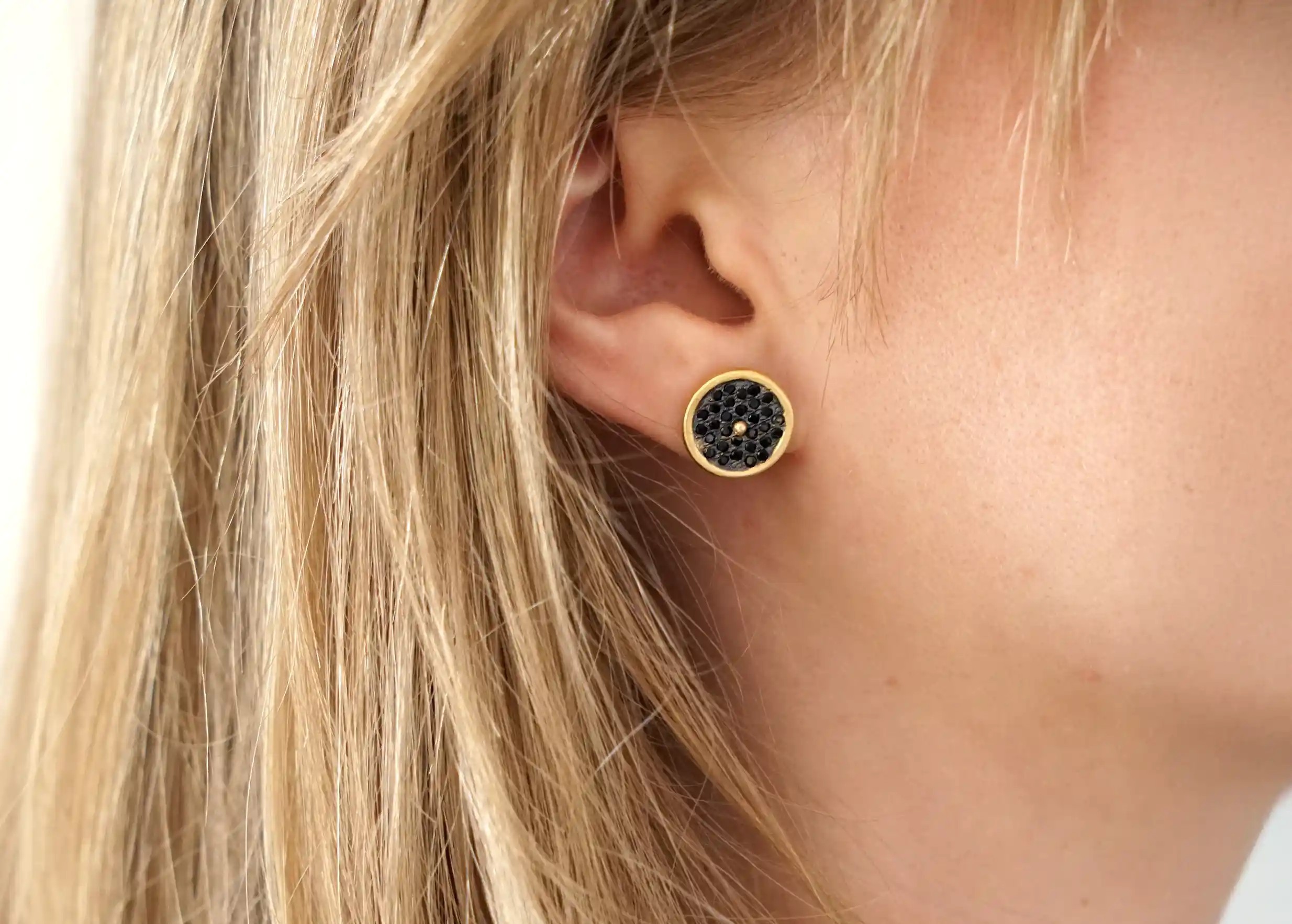 Boucle d'oreille clous en laiton et zirconium portée à l'oreille d'une femme, collection Nuit des Temps