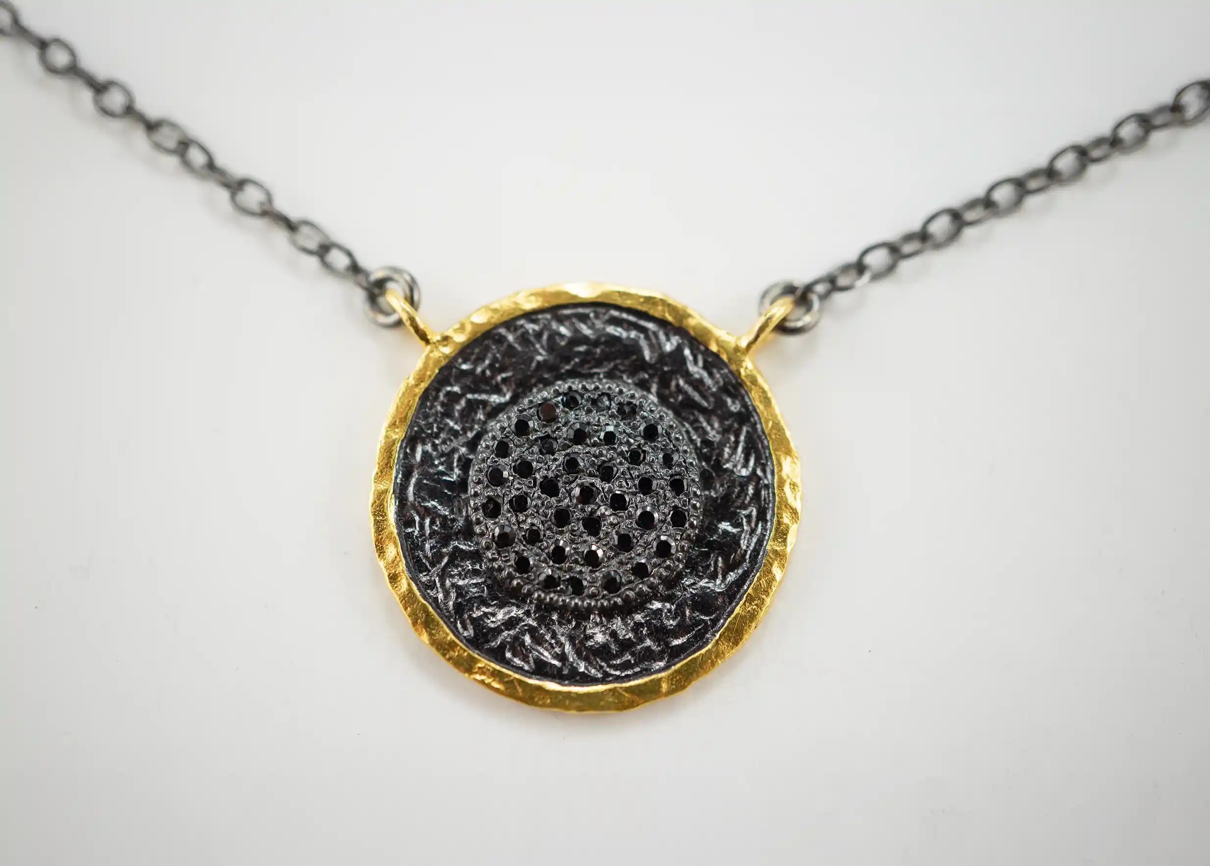 Focus on the brass and zirconium pendant from the Dawn of Time collection