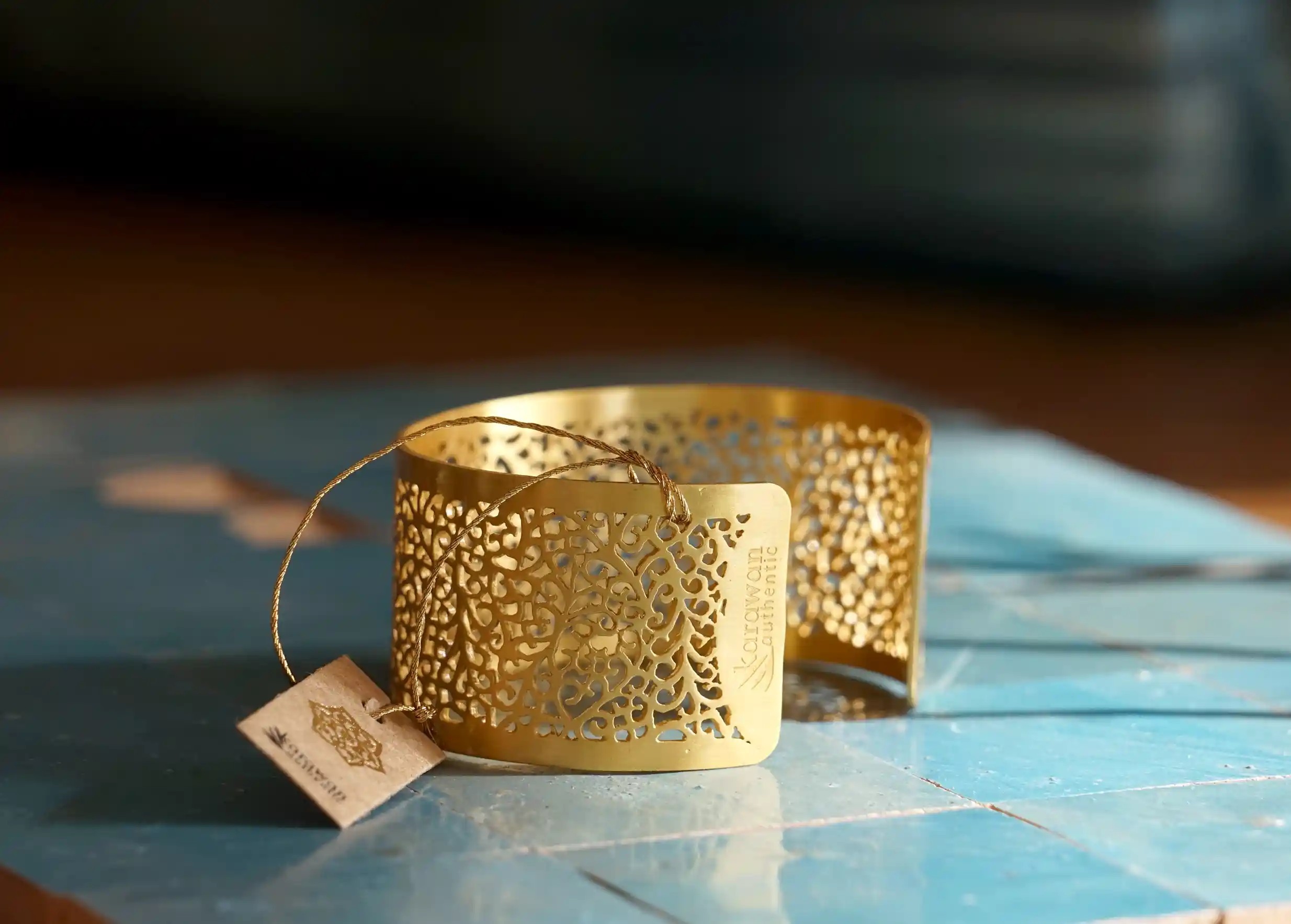 Manchette en laiton Karawan de la collection Jardin Secret posée sur une surface à carreaux bleus