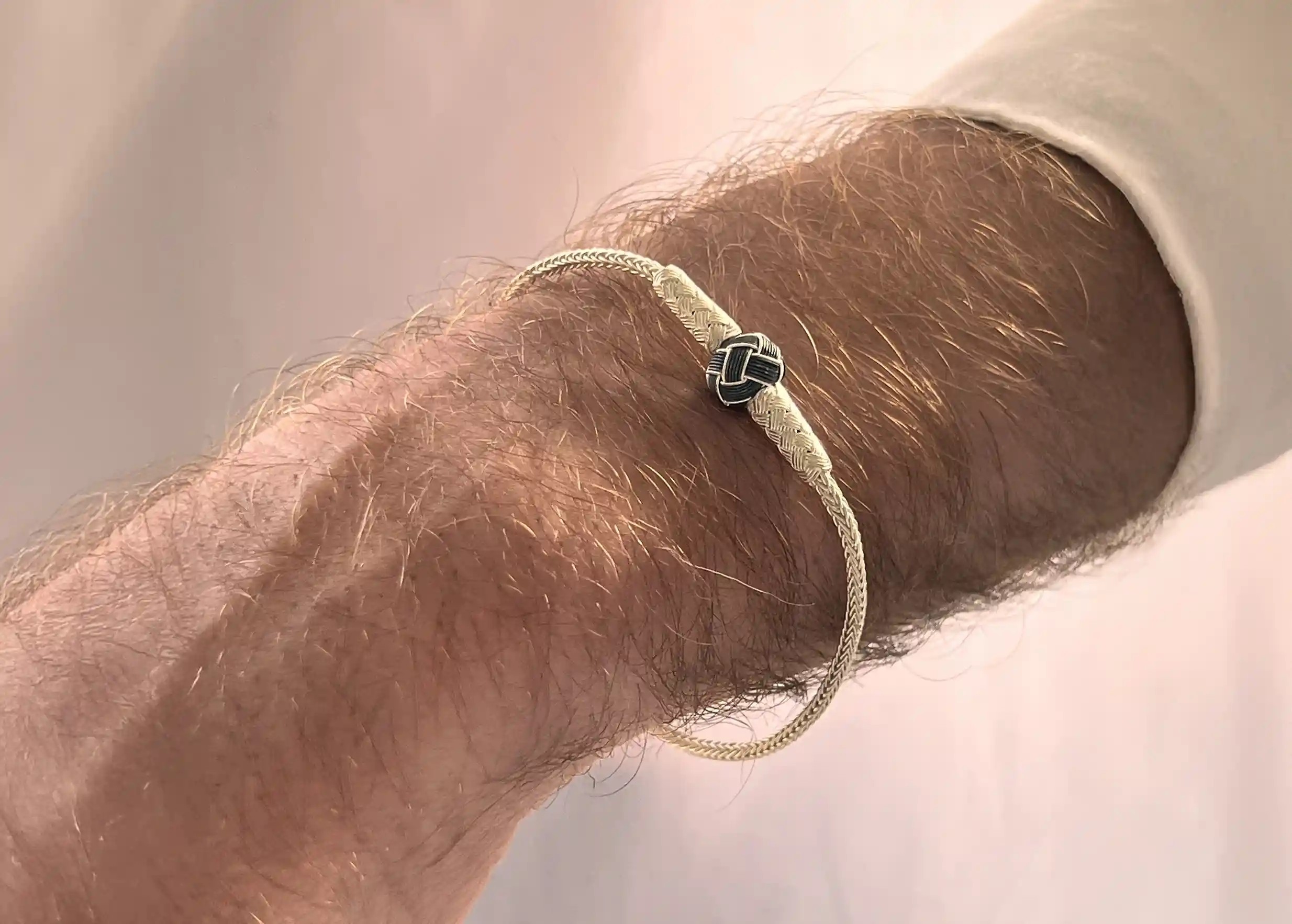 Silver bracelet from the Kokaz jewellery collection with a black bow, worn by one person.