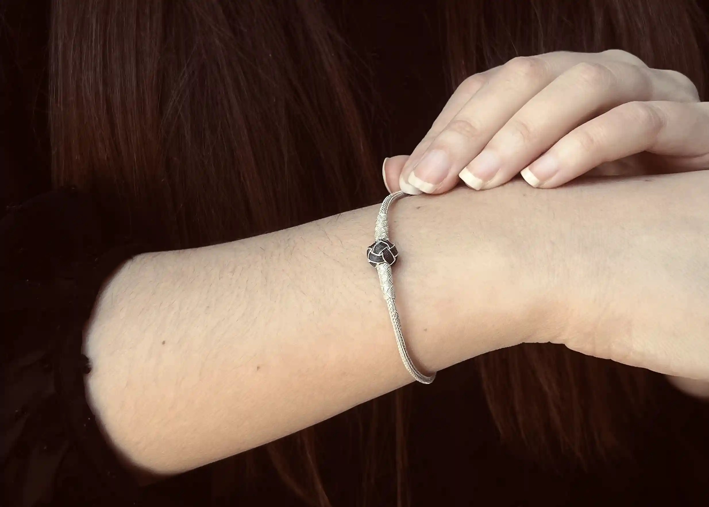 Silver bracelet from the Kokaz jewellery collection with a black bow, worn by a woman