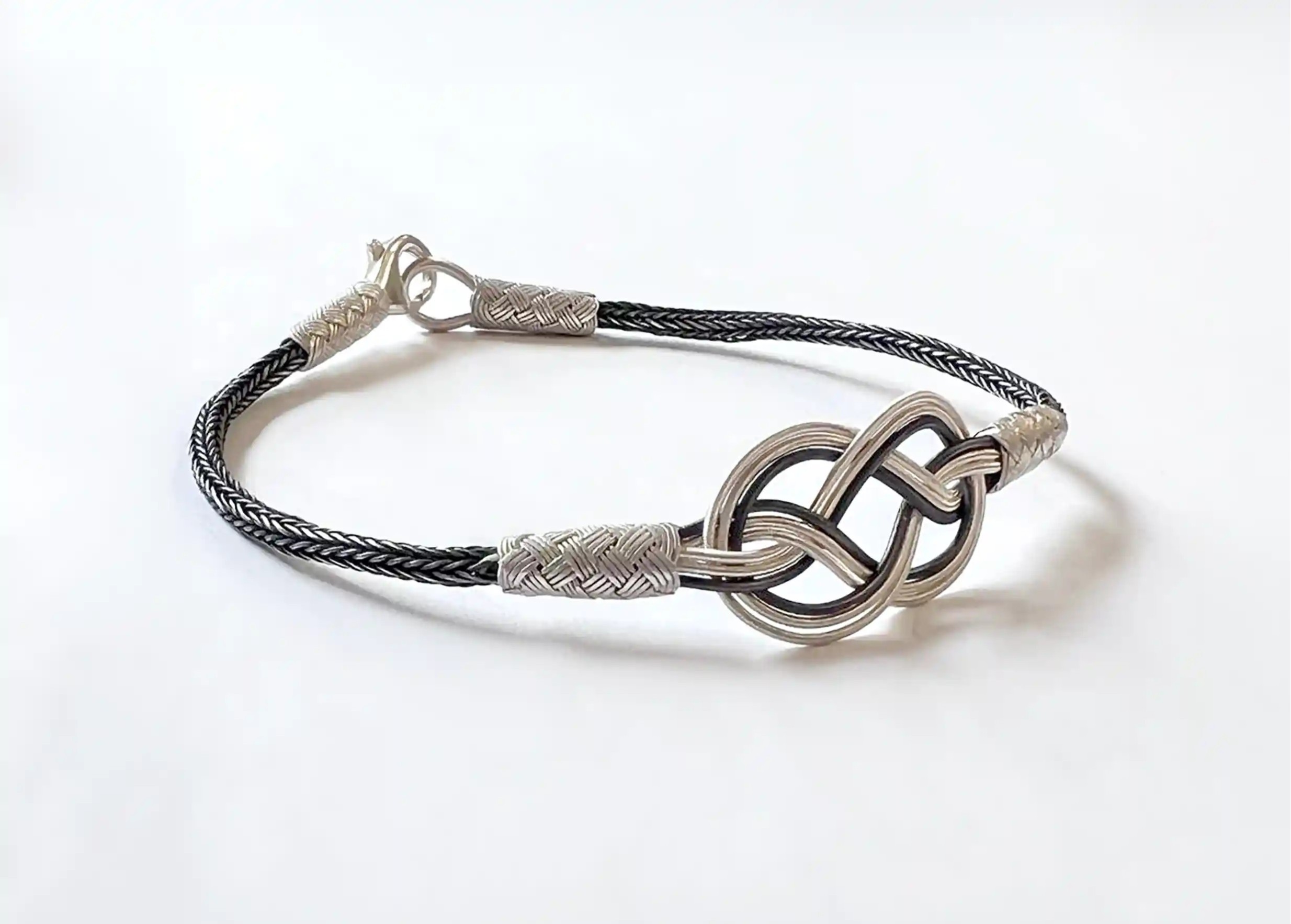 Silver and oxidised silver bracelet from the Kokaz jewellery collection ‘Infinity’ model, set on a clear surface