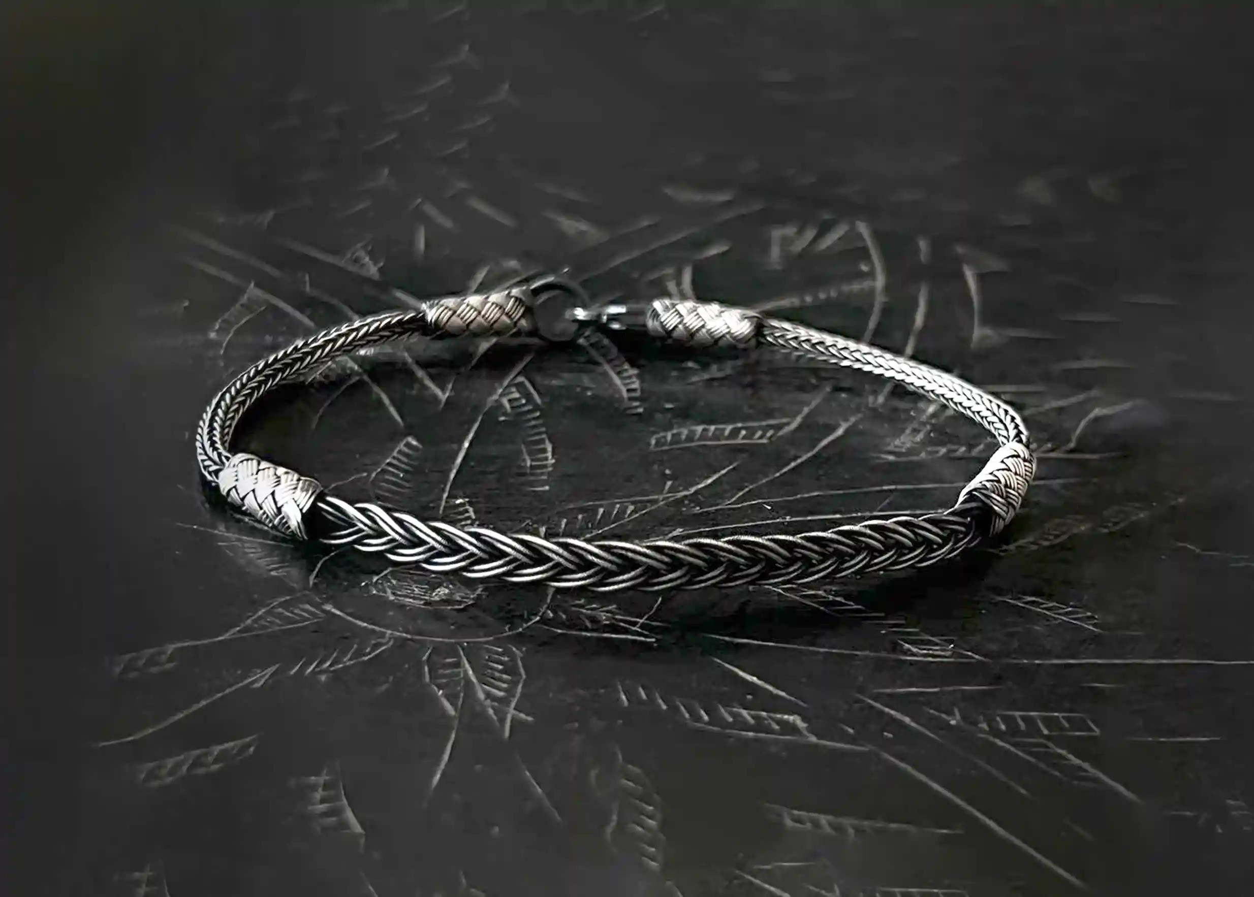 Silver and oxidized silver bracelet from the Kokaz jewellery collection, ‘fine braid’ model, set on a black surface