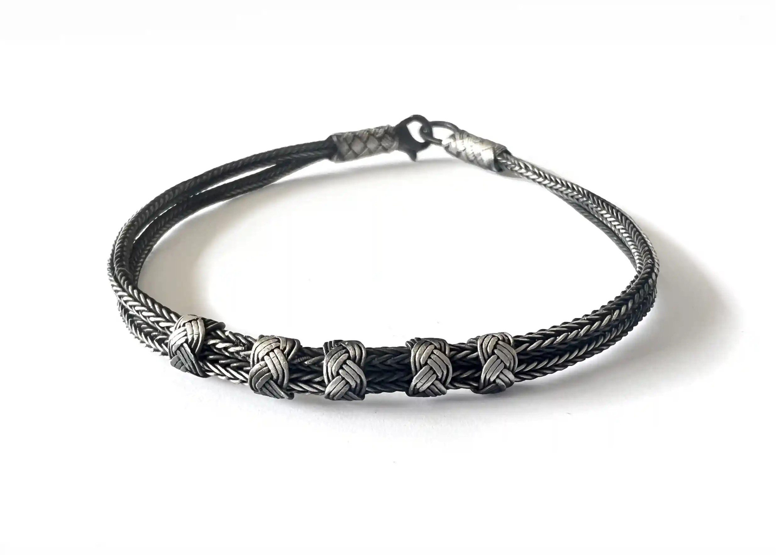 Silver bracelet from the Kokaz jewellery collection, fine double braid and 5 knots on a white background