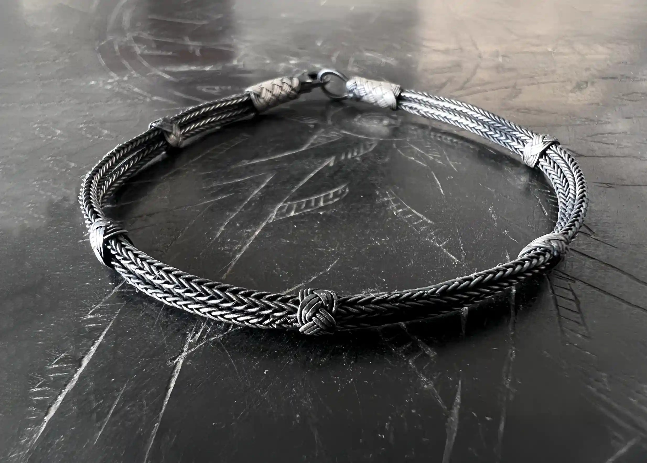 Silver bracelet from the Kokaz jewellery collection, woven with 5 knots on a black surface