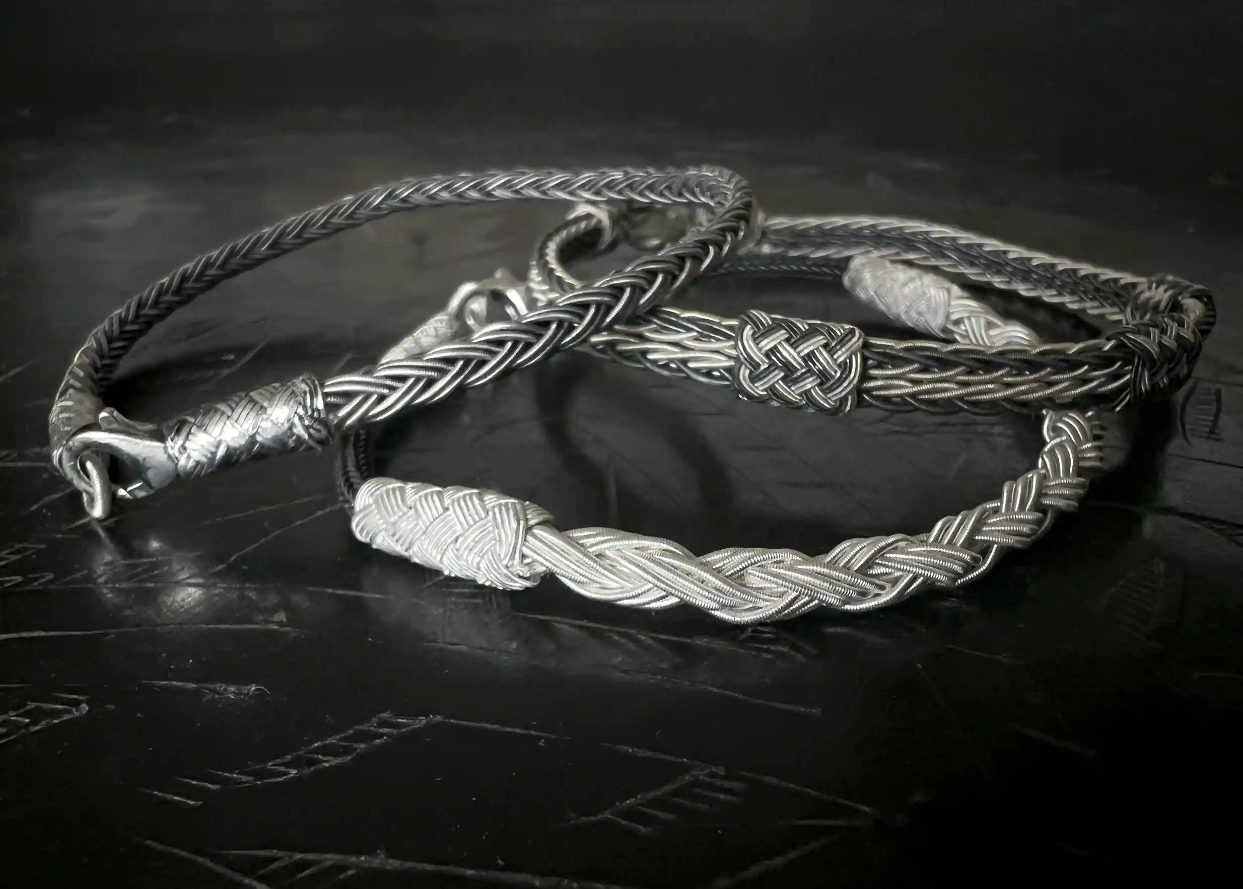 Three bracelets from the KOKAZ jewellery collection, placed on a black surface