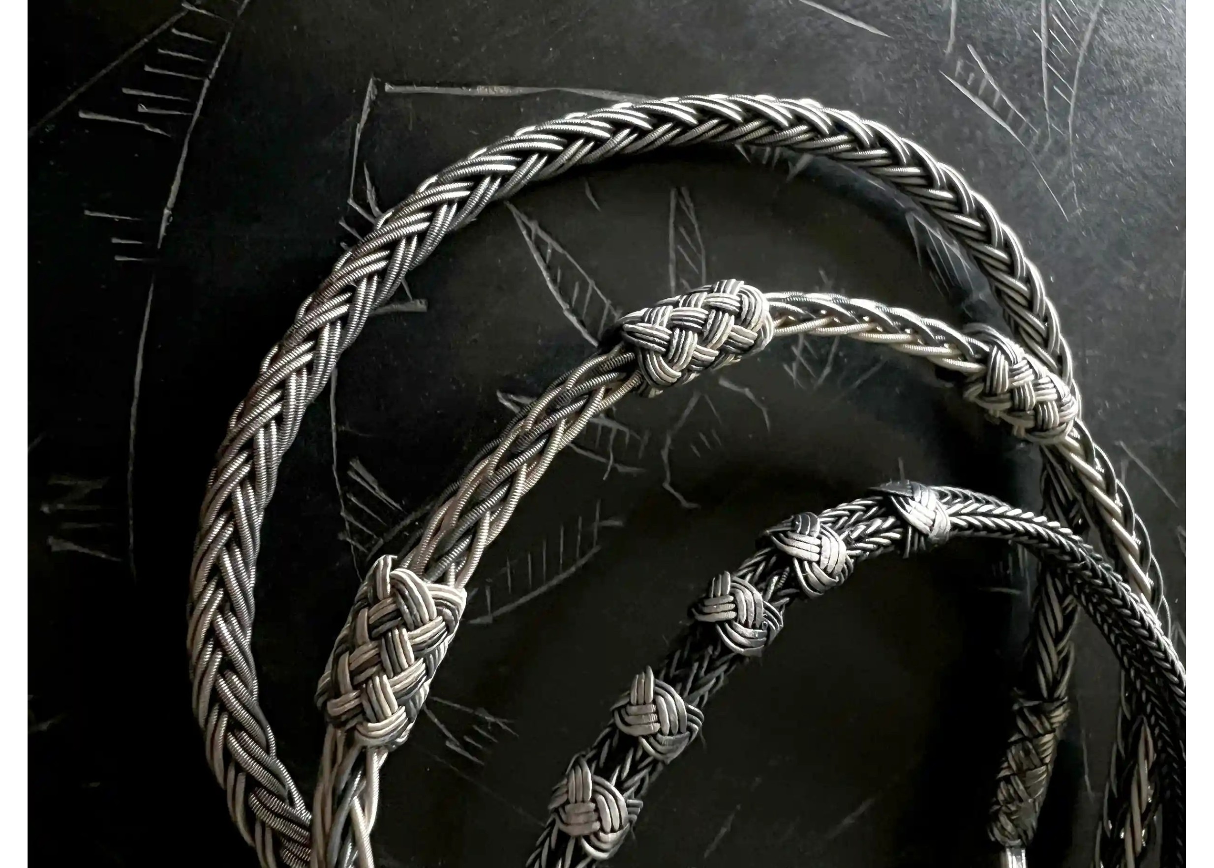 Three bracelets from the Kokaz handmade jewellery collection, placed on a black surface