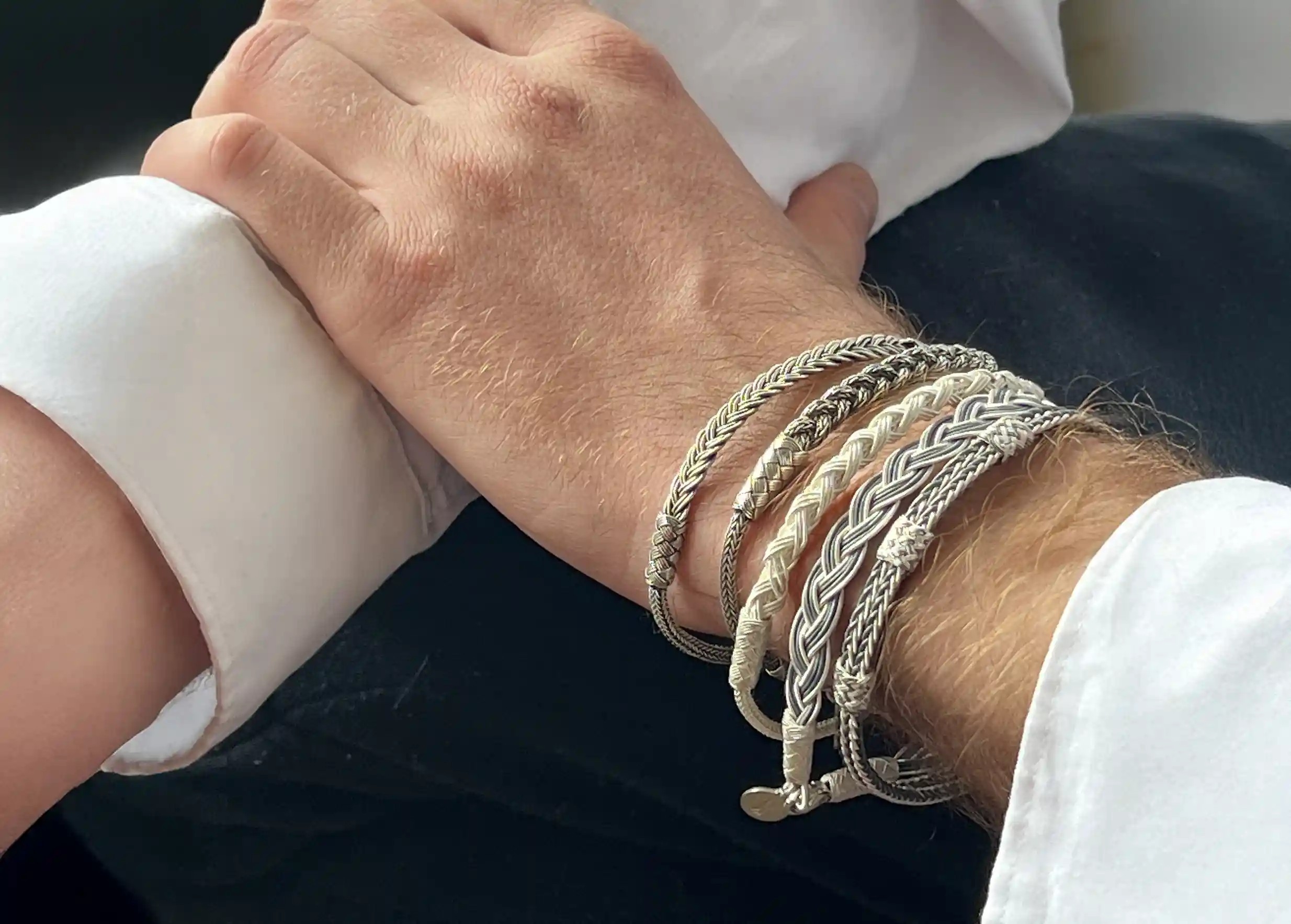 Man wearing several silver bracelets from the Kokaz jewellery collection on one of his wrists