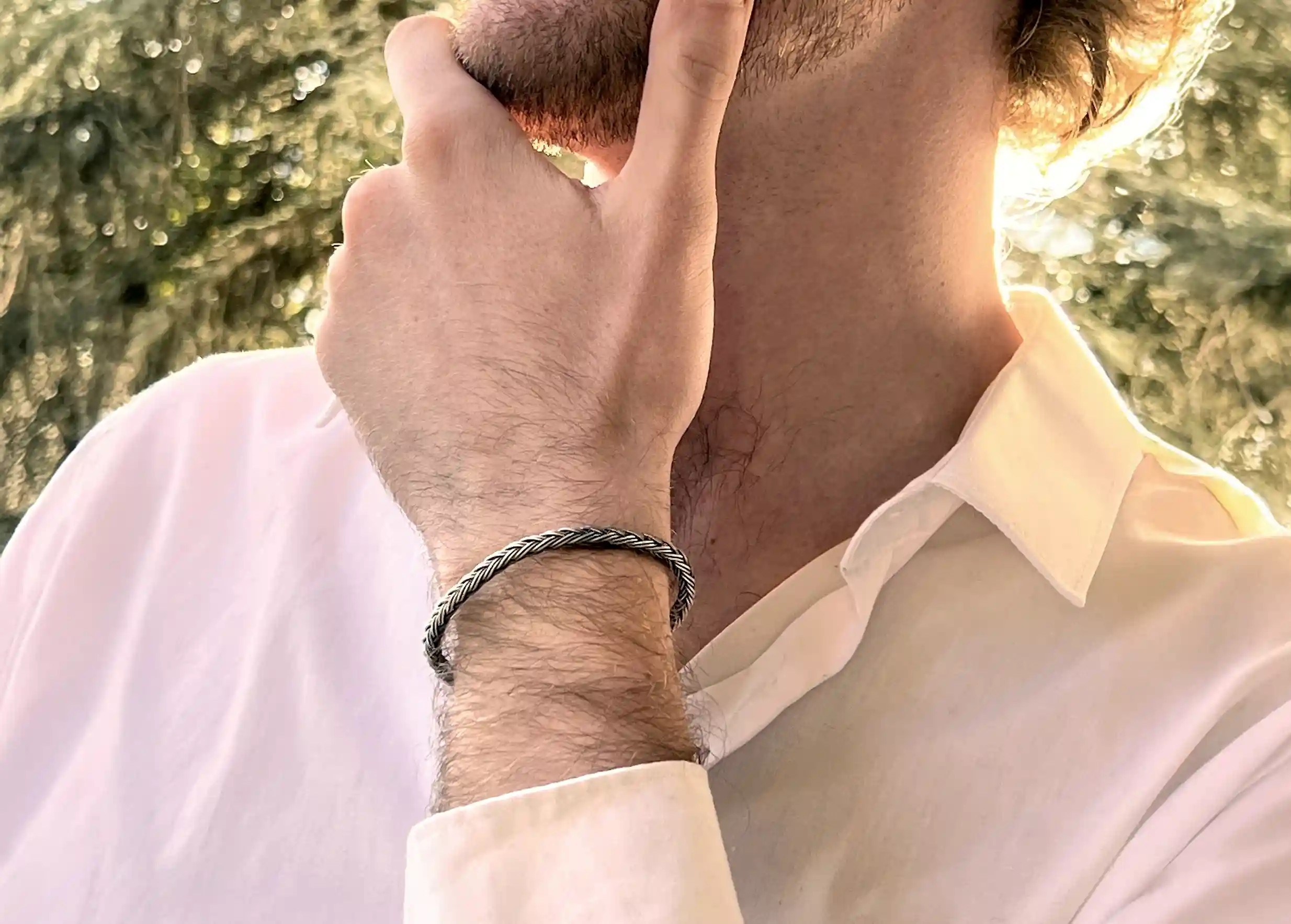 Silver bracelet from the Kokaz jewellery collection, round braided design with metal clasp, worn on a man's wrist.