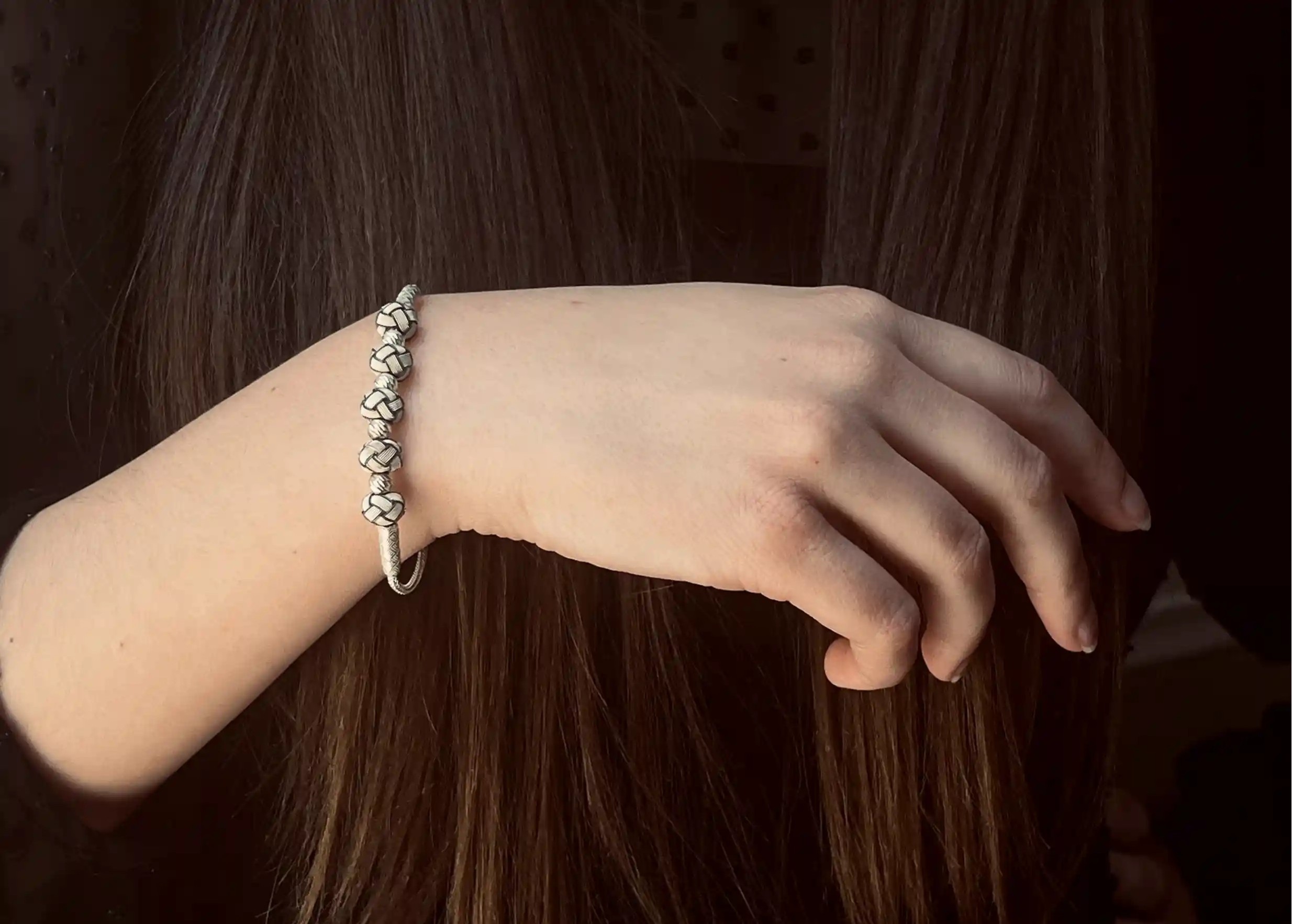 Silver bracelet from the Kokaz jewellery collection with 5 white bows, worn by one person
