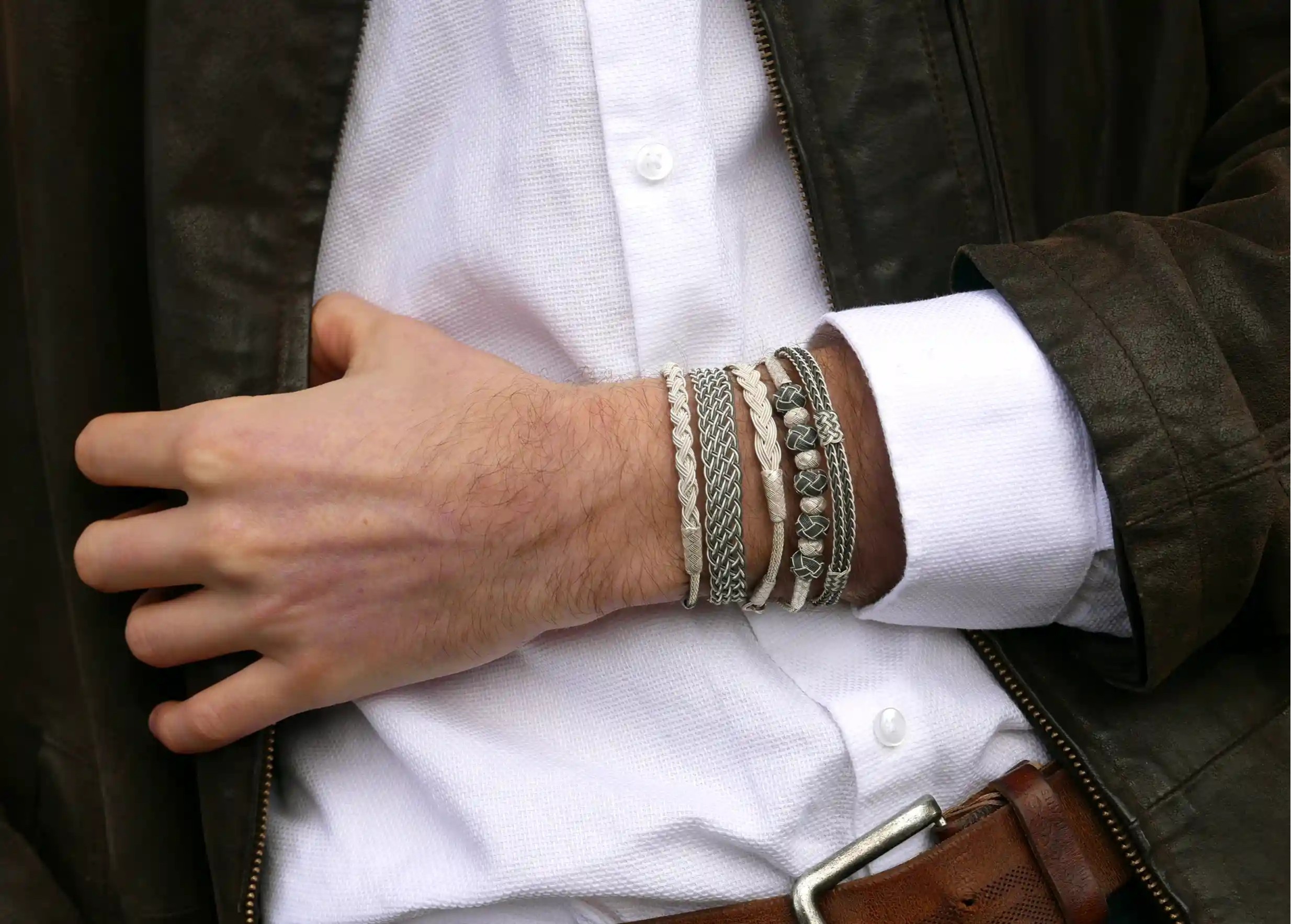 Man wearing a set of silver bracelets from the KOKAZ jewellery collection on his wrist.