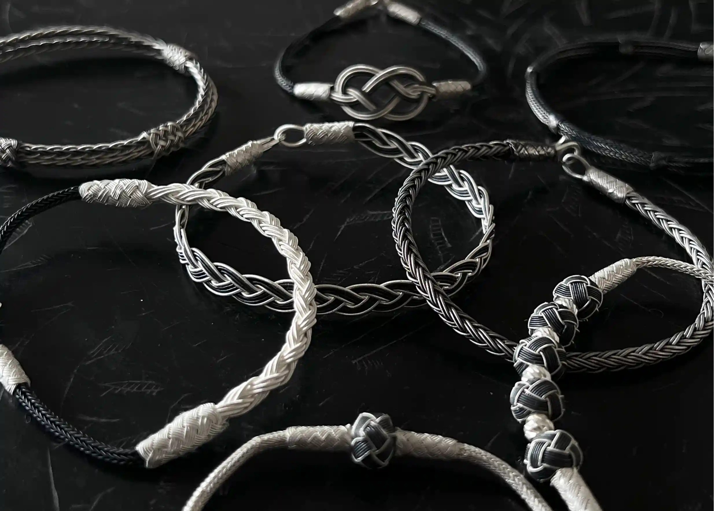 Silver and oxidised silver jewellery from the Kokaz jewellery collection with braided rope, set on a black surface