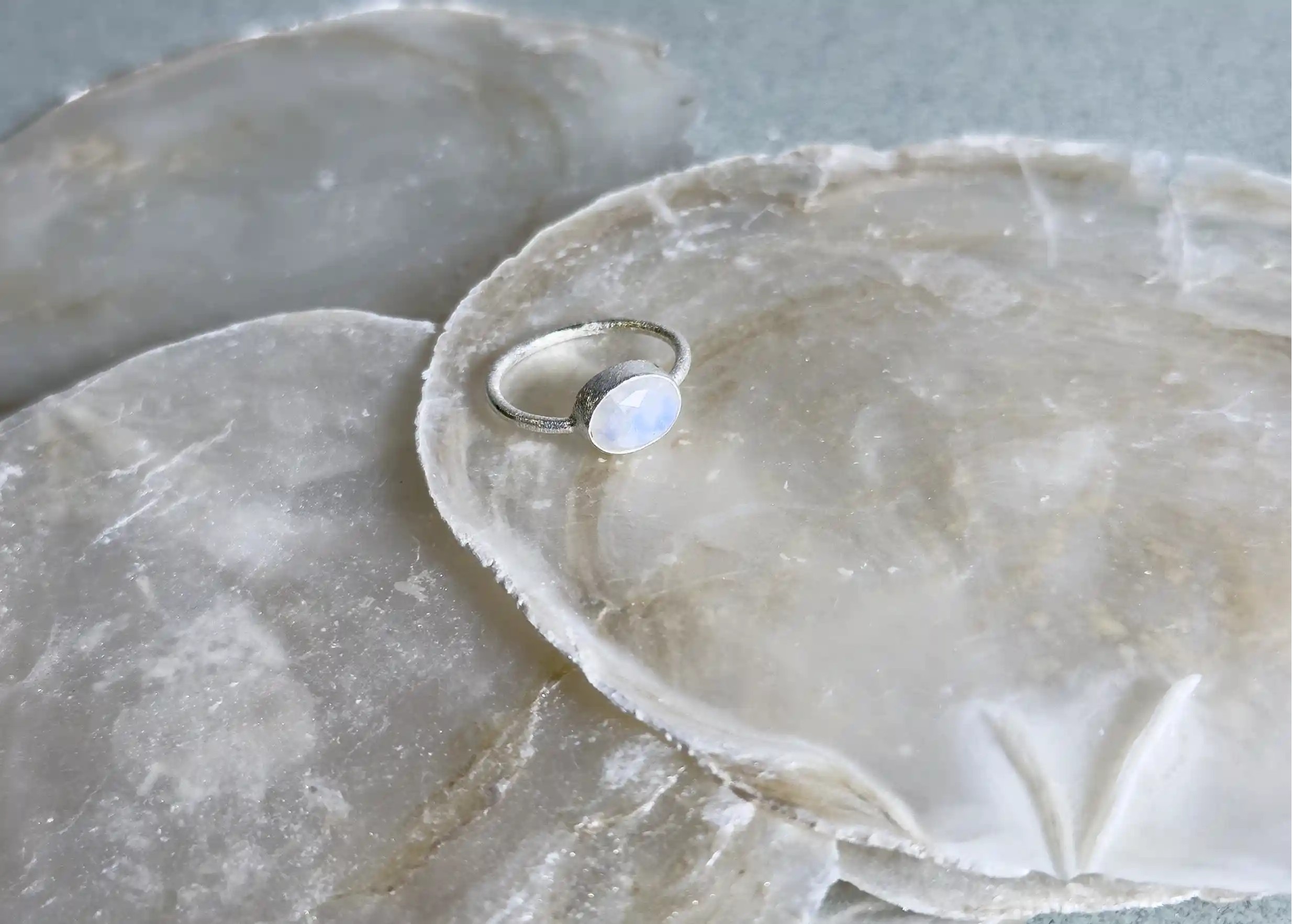Zoom sur les reflets de la bague en argent 925 Drop moonstone de la collection de bijoux Yamuna, exposé sur une pierre
