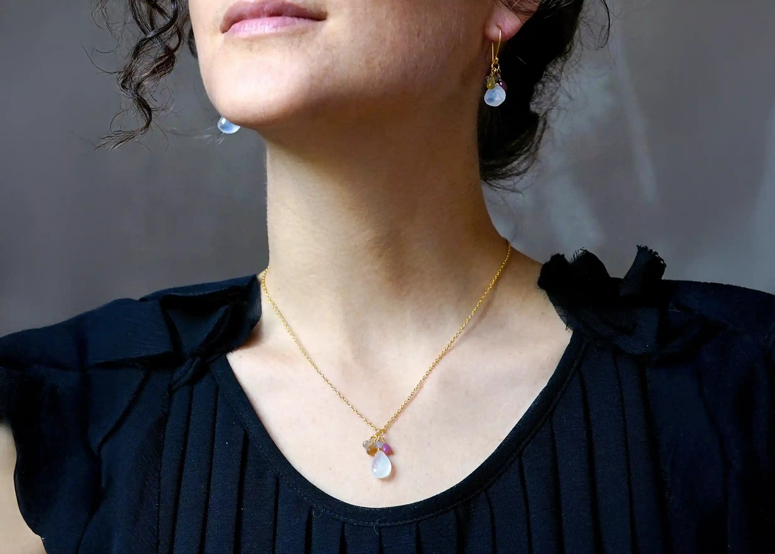 Silver and gold Grapes pendant, moonstone from the Yamuna jewellery collection, worn by a woman indoors