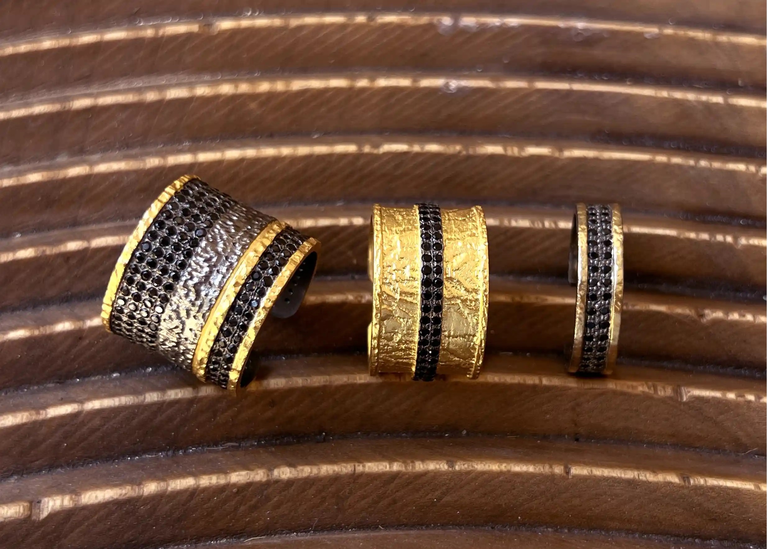 Collection de bijoux en laiton comprenant des bagues, présentés sur un support en bois