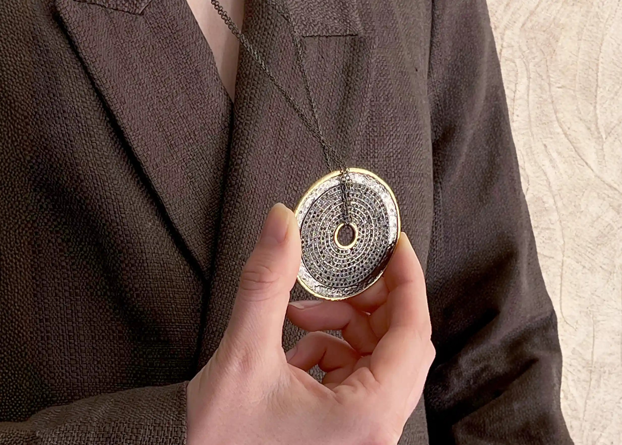 Sautoir talisman avec double chaine ajustable tenu des doigts par une personne, collection Nuit des Temps