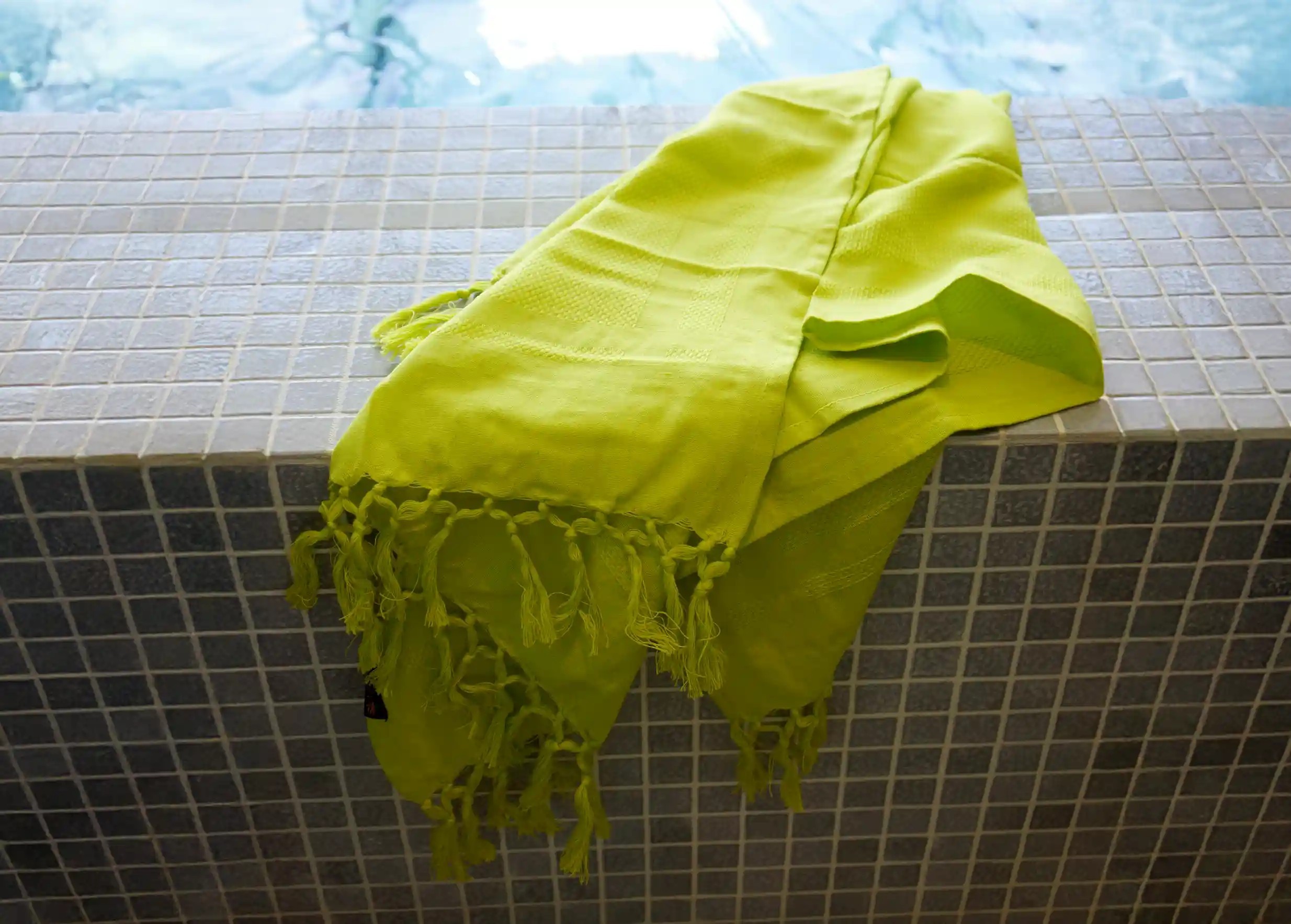 Basil-coloured green fouta on the edge of a swimming pool