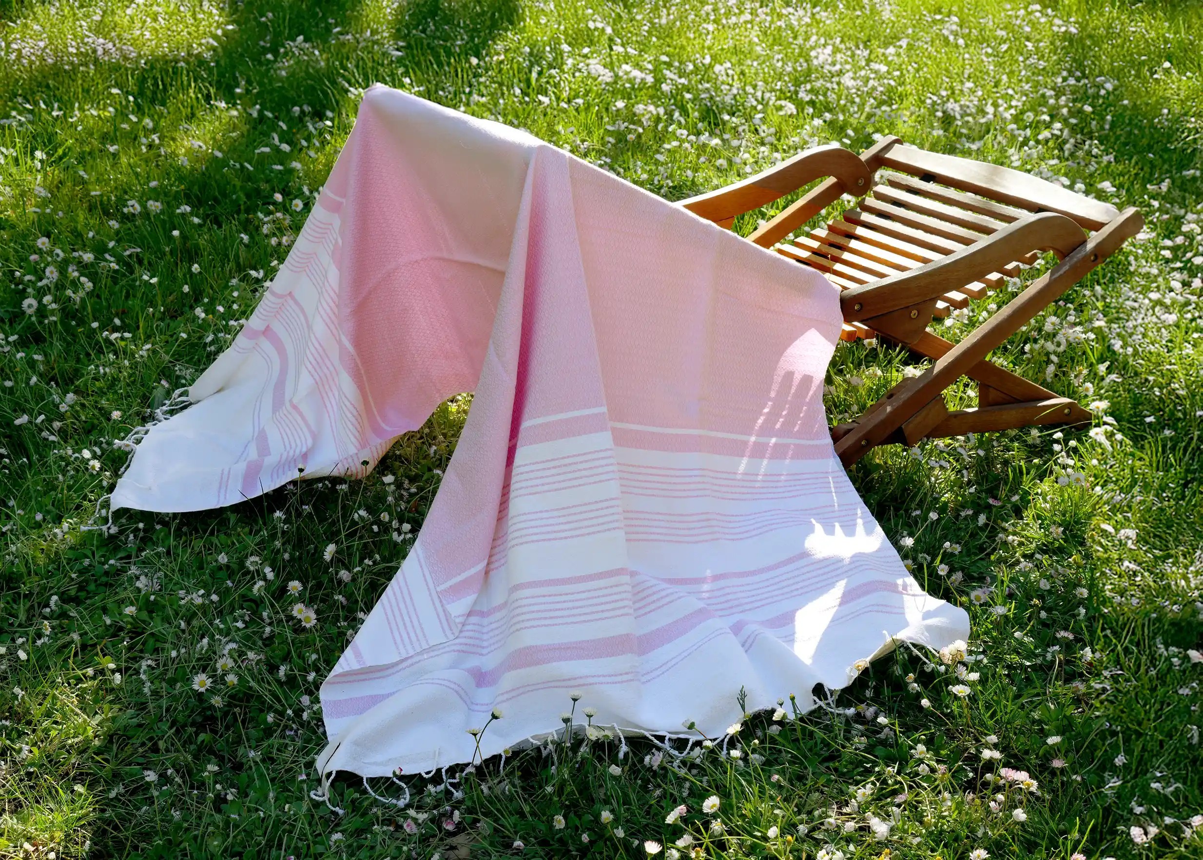 Fouta en coton bio coloris Parme, collection White Sand, aux rayures blanches et violettes, drapée sur une chaise
