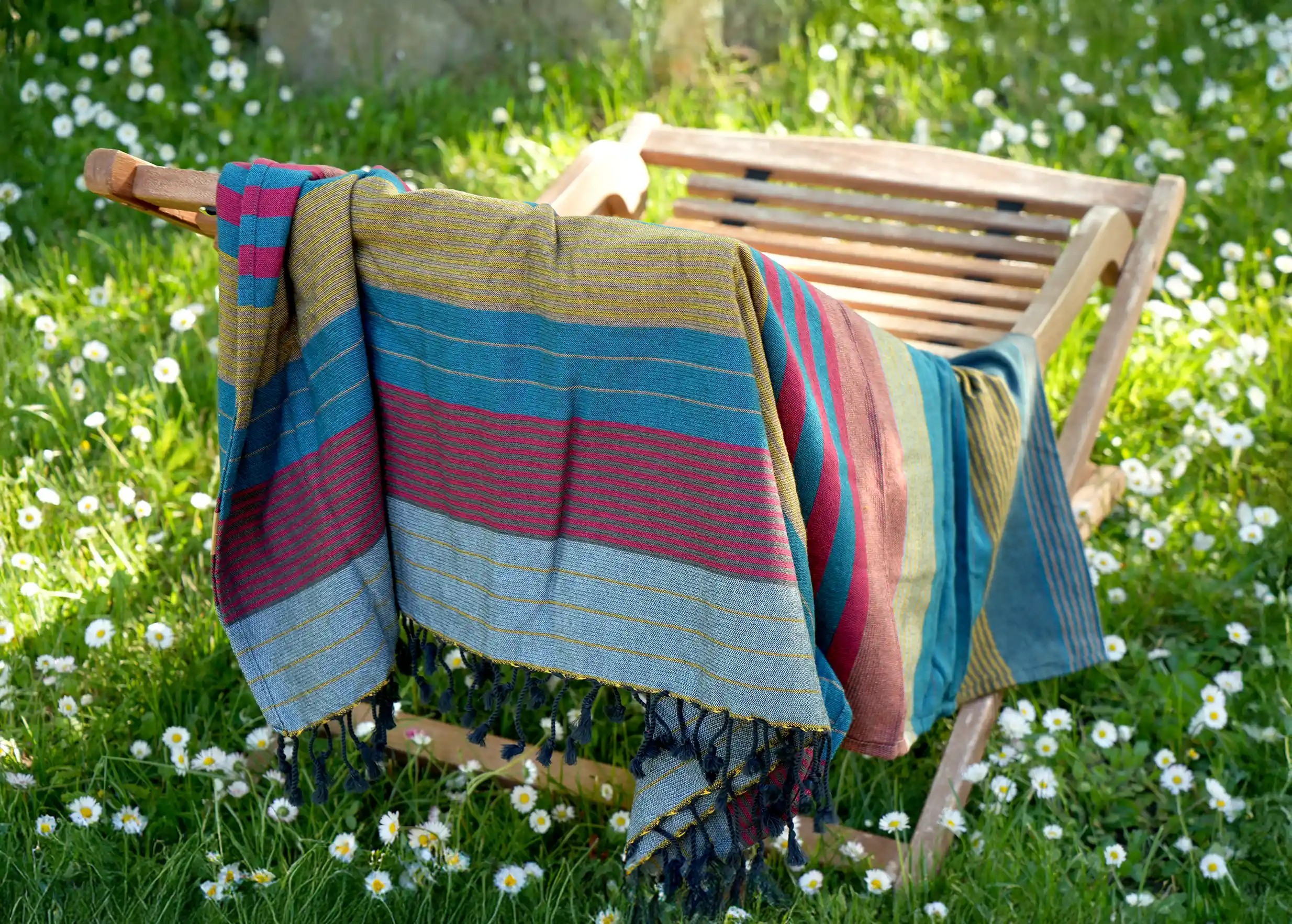 Fouta coloris rouge et bleu dressée comme une serviette de table dans un jardin