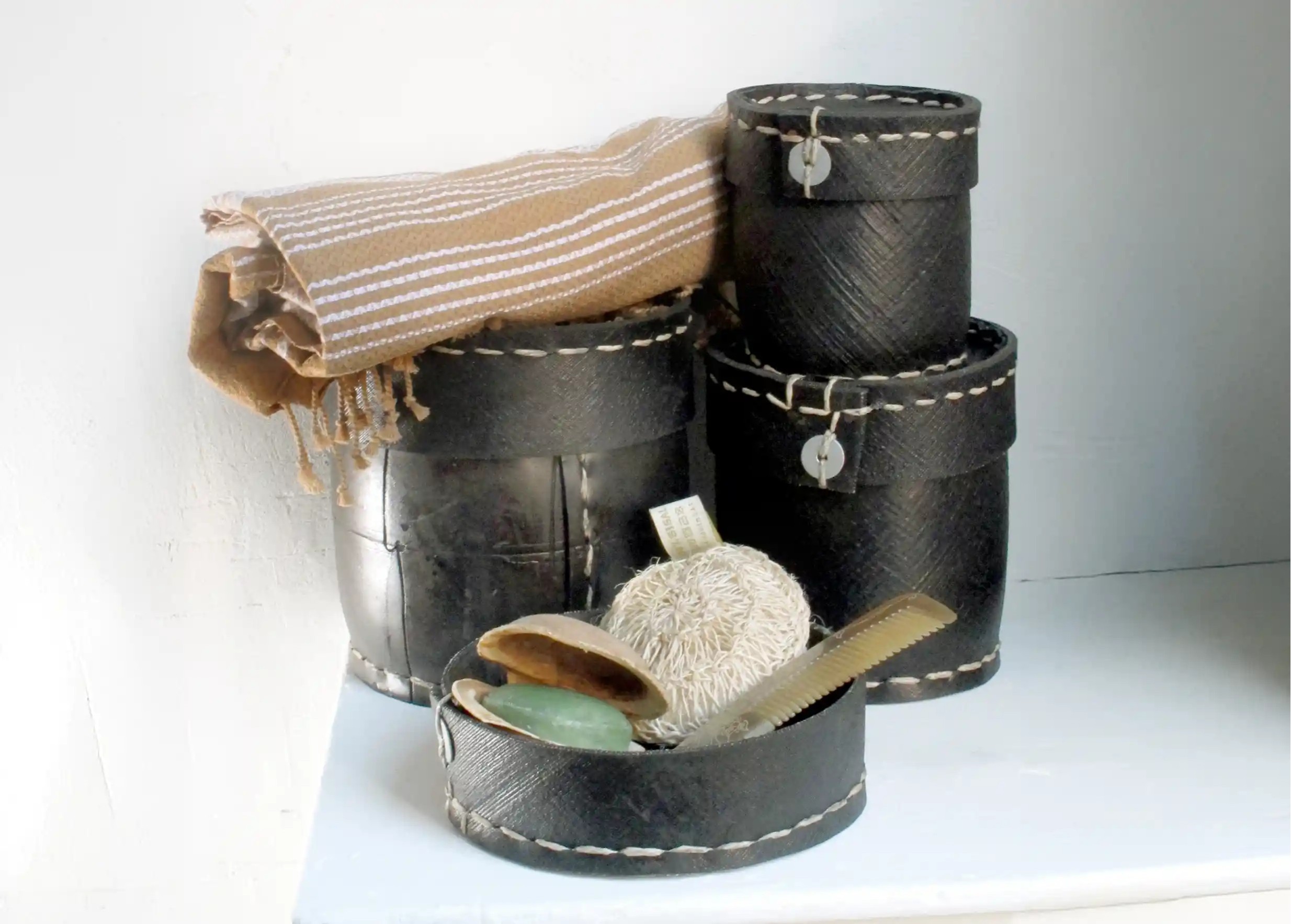 A set of recycled tyre pots used for decorative storage, accompanied by a fouta and accessories.