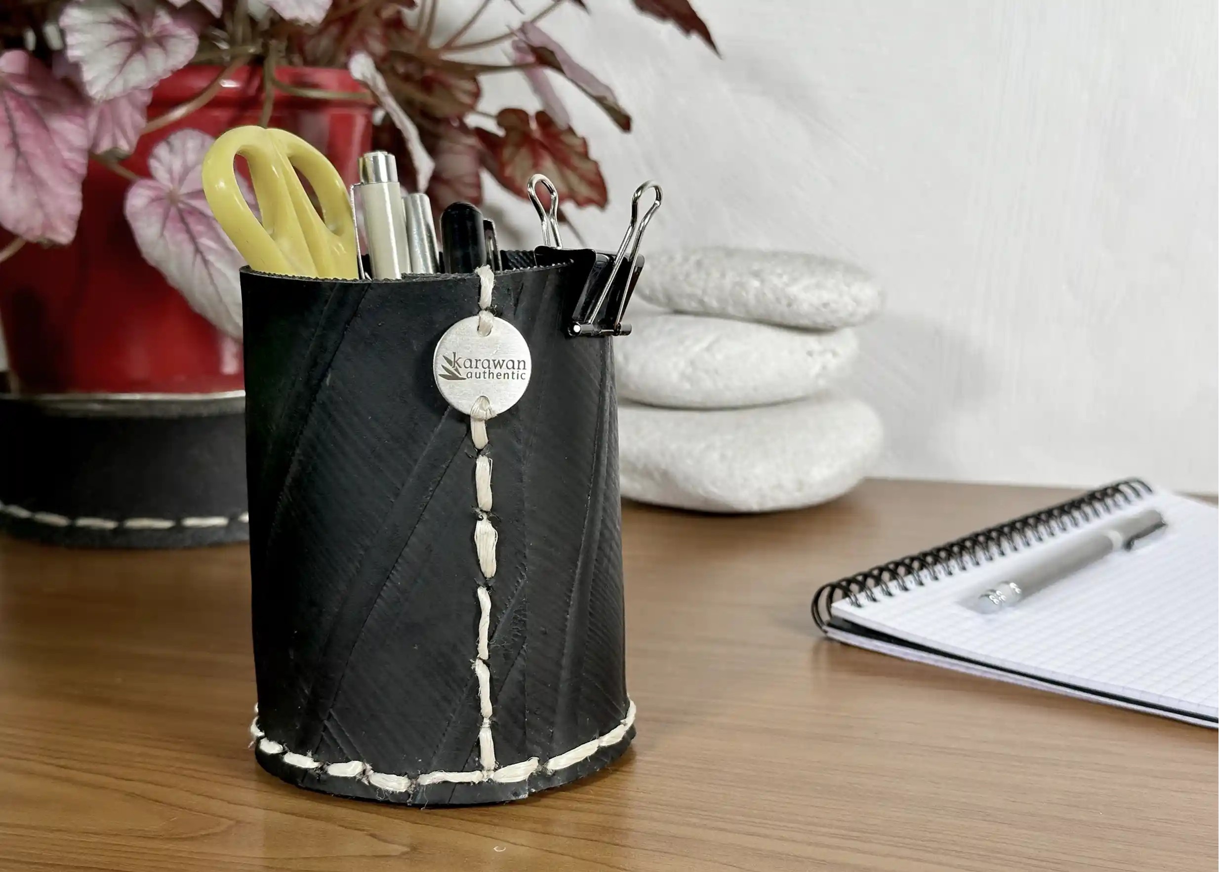 Small straight pot in black recycled tyre on a desk, hand-stitched and engraved Karawan authentic button