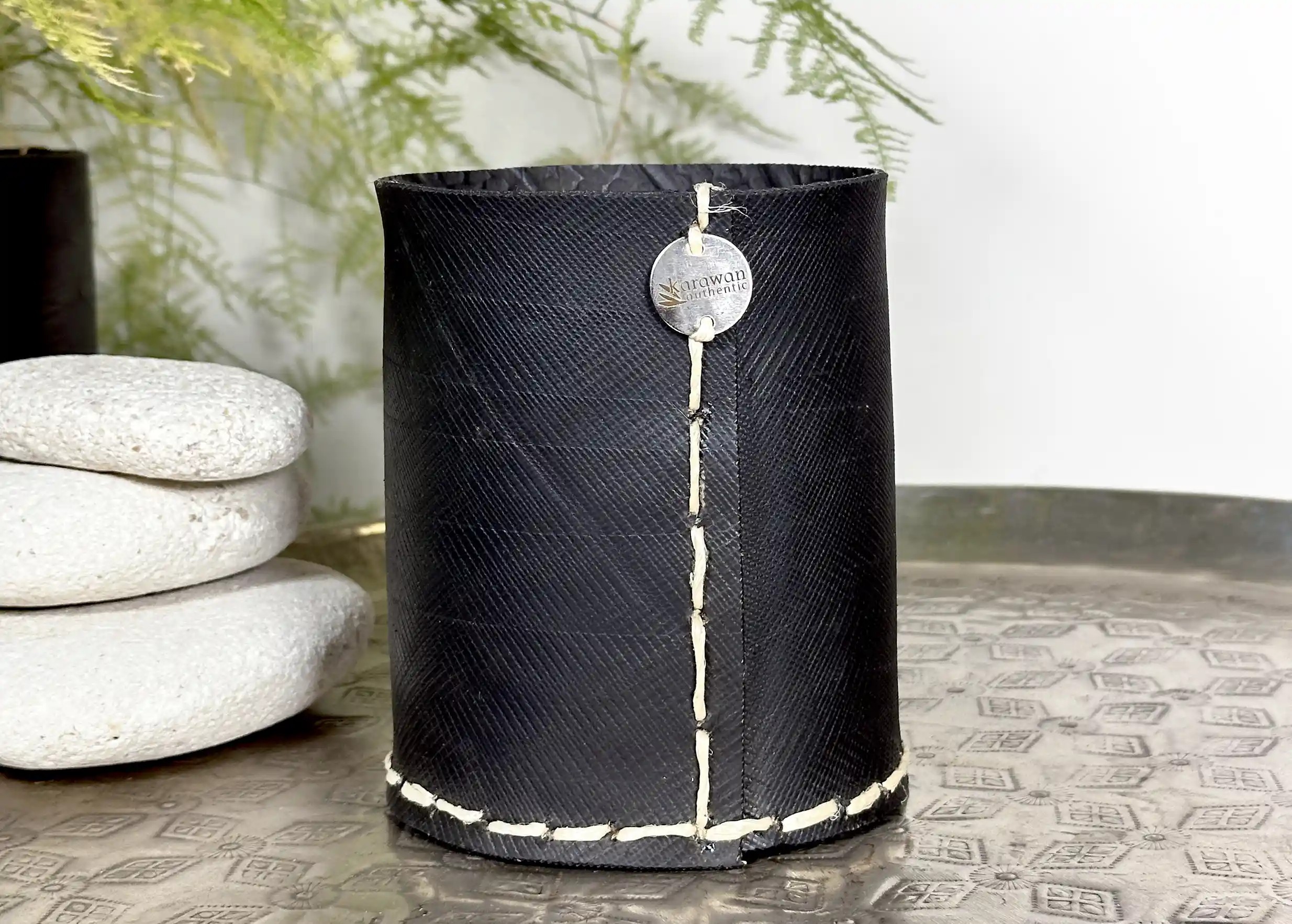 Medium upright pot in recycled tyres next to pebbles, on a brass tray