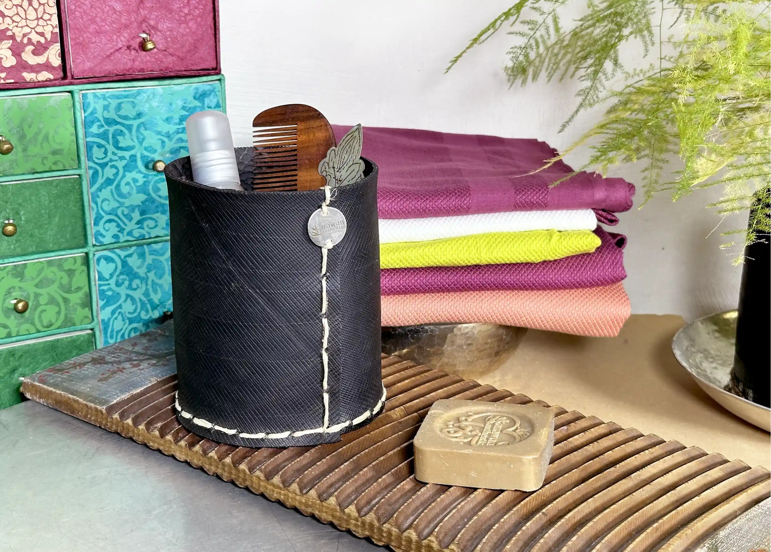 Medium straight pot in black recycled tyre with visible stitching, next to several foutas and an Aleppo soap.