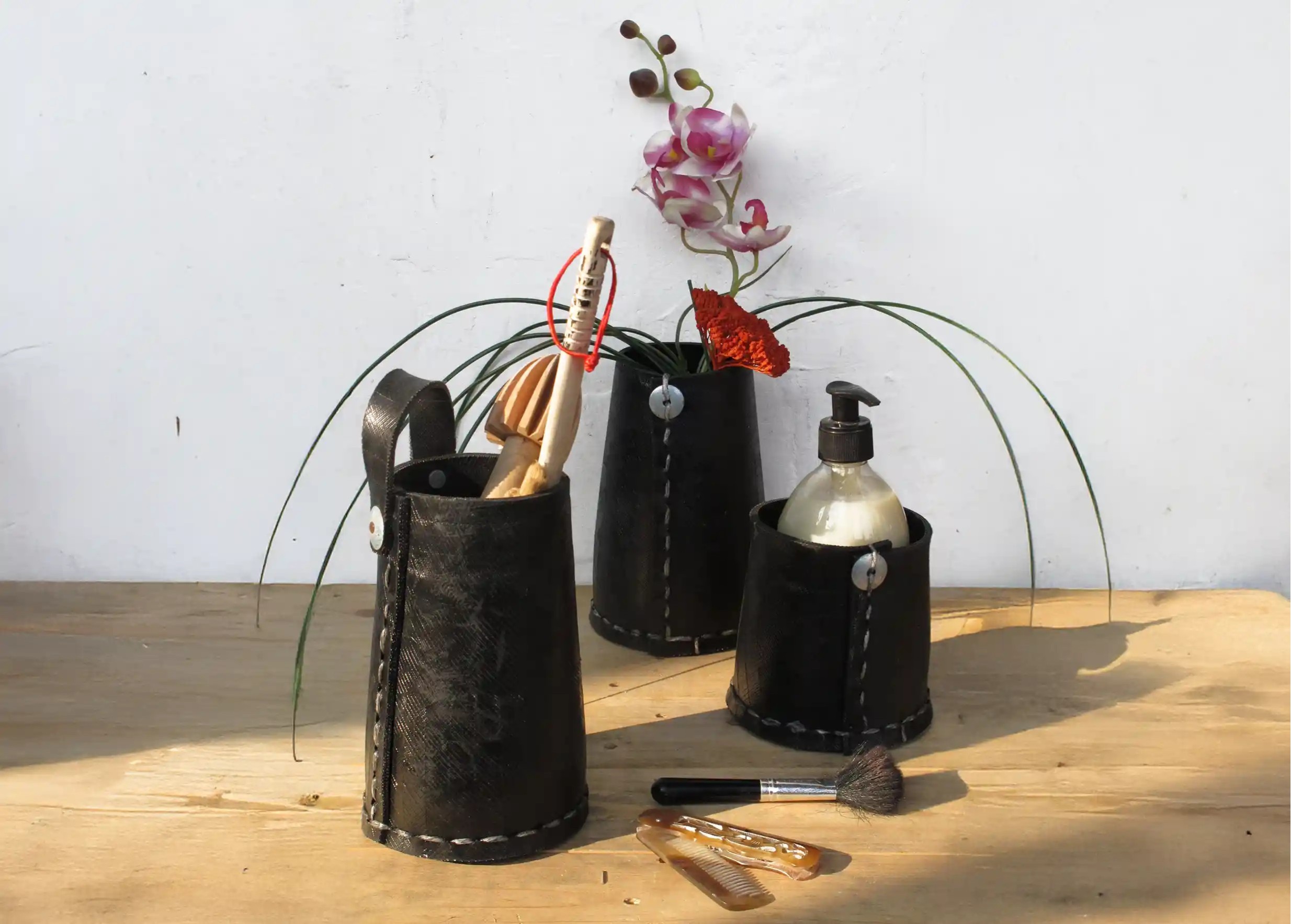 3 tall black pots made from recycled tyres, used to store toiletries, flowers and plants