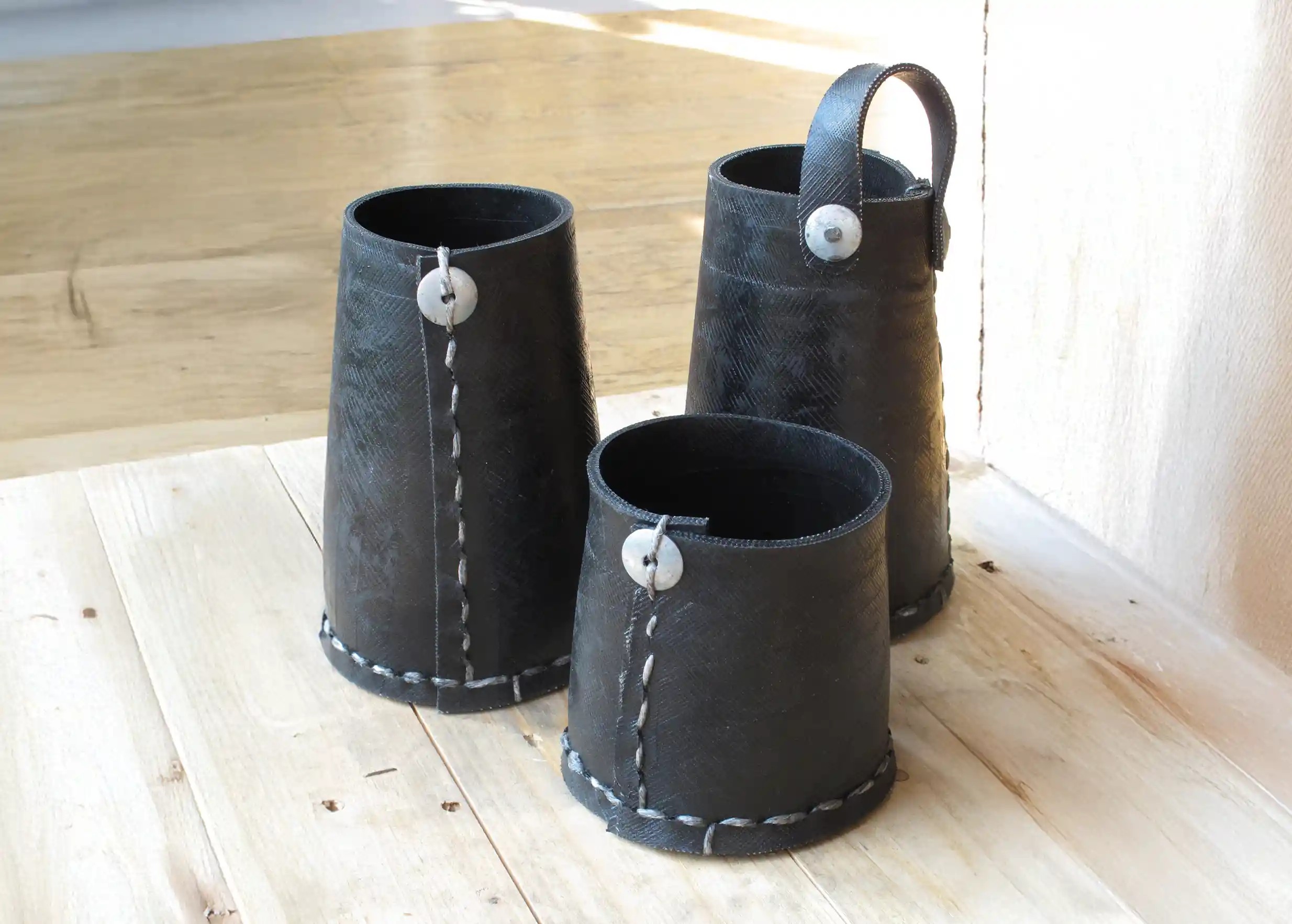 3 pots hauts noirs en pneu recyclé de la marque Karawan, au sol