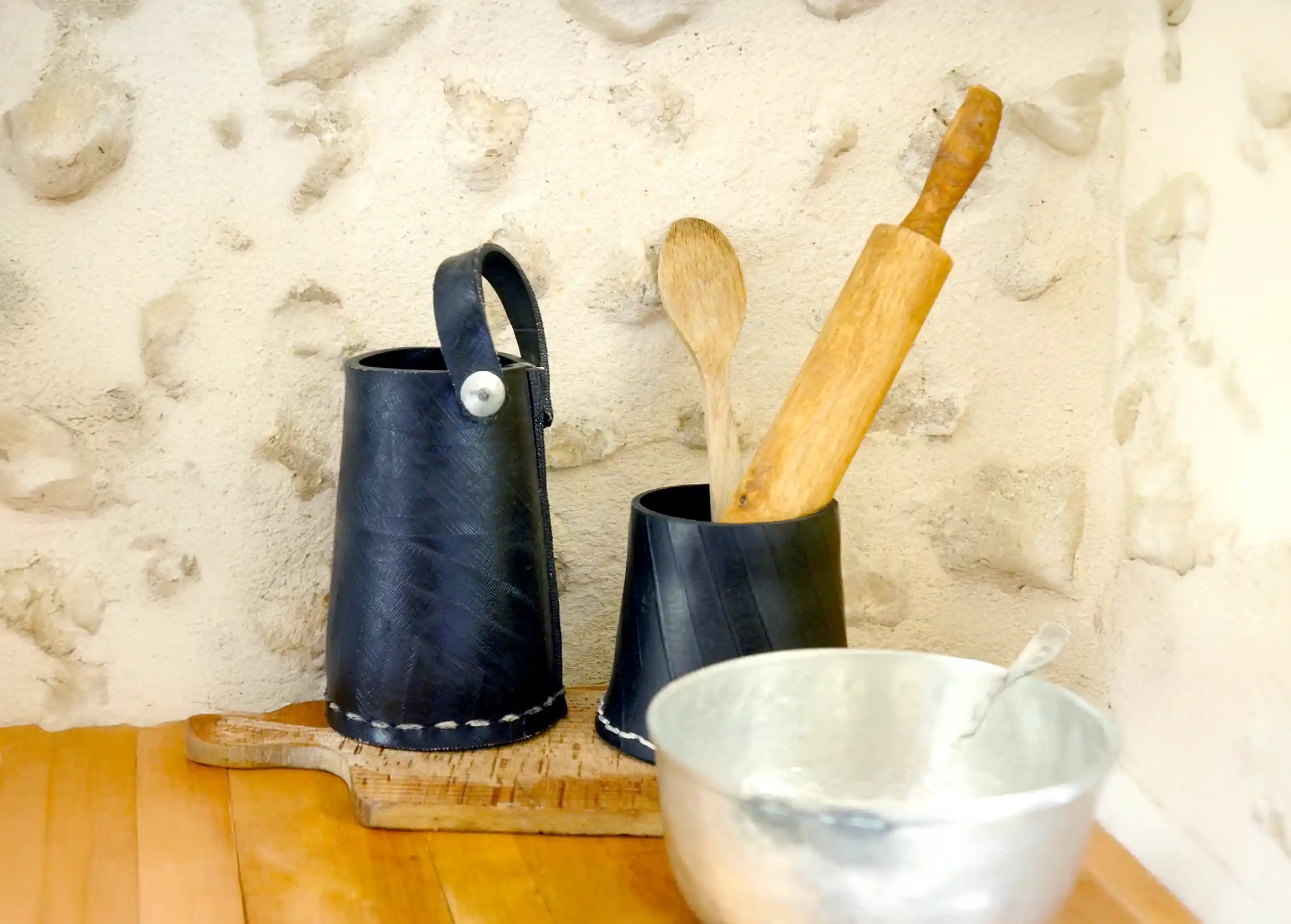 2 tall black pots made from recycled tyres, used to store kitchen items, flowers and plants