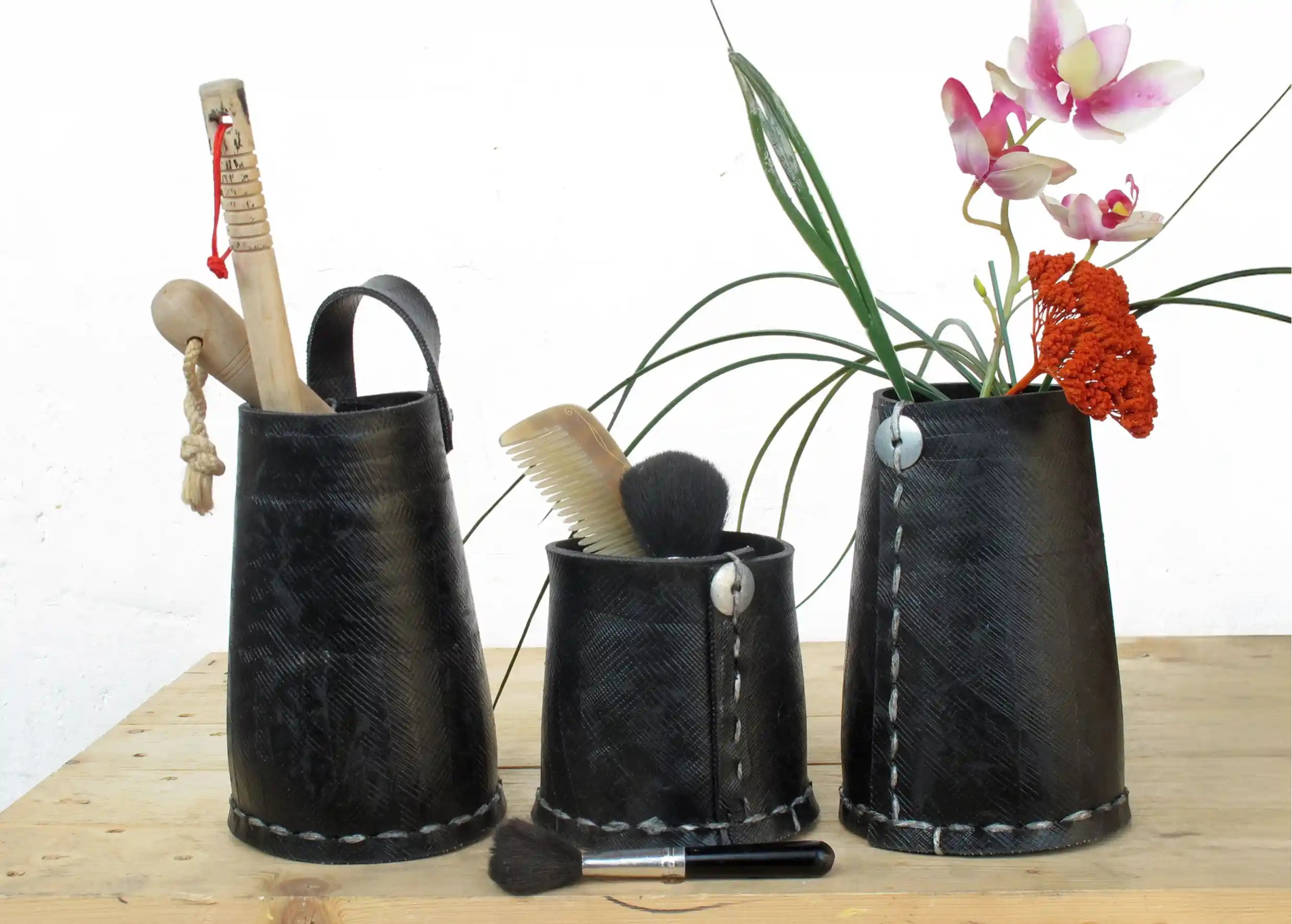 3 tall black pots made from recycled tyres, used to store accessories, flowers and plants