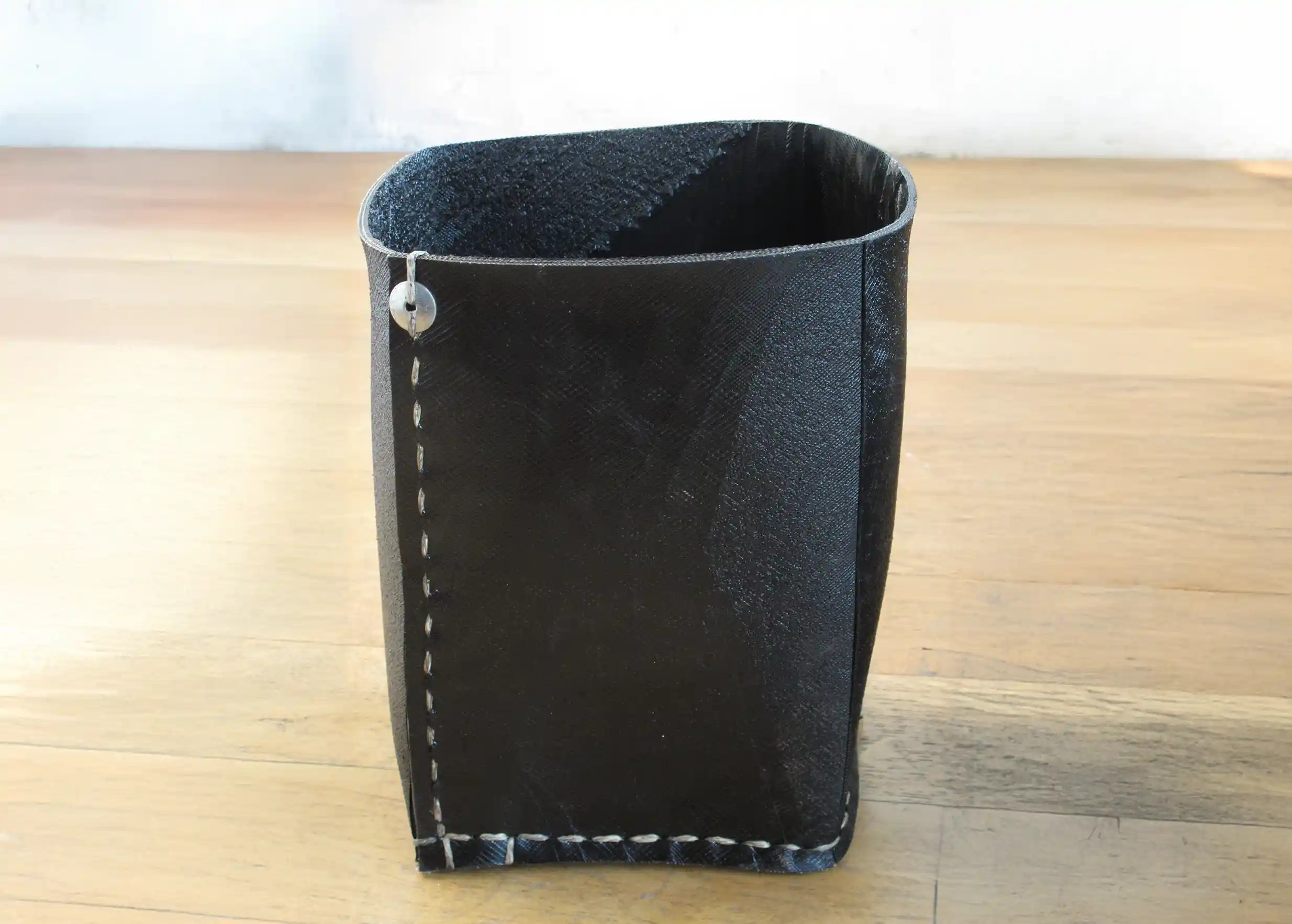 A tall black pot without a handle, made from recycled tyres by Karawan, on a white background.