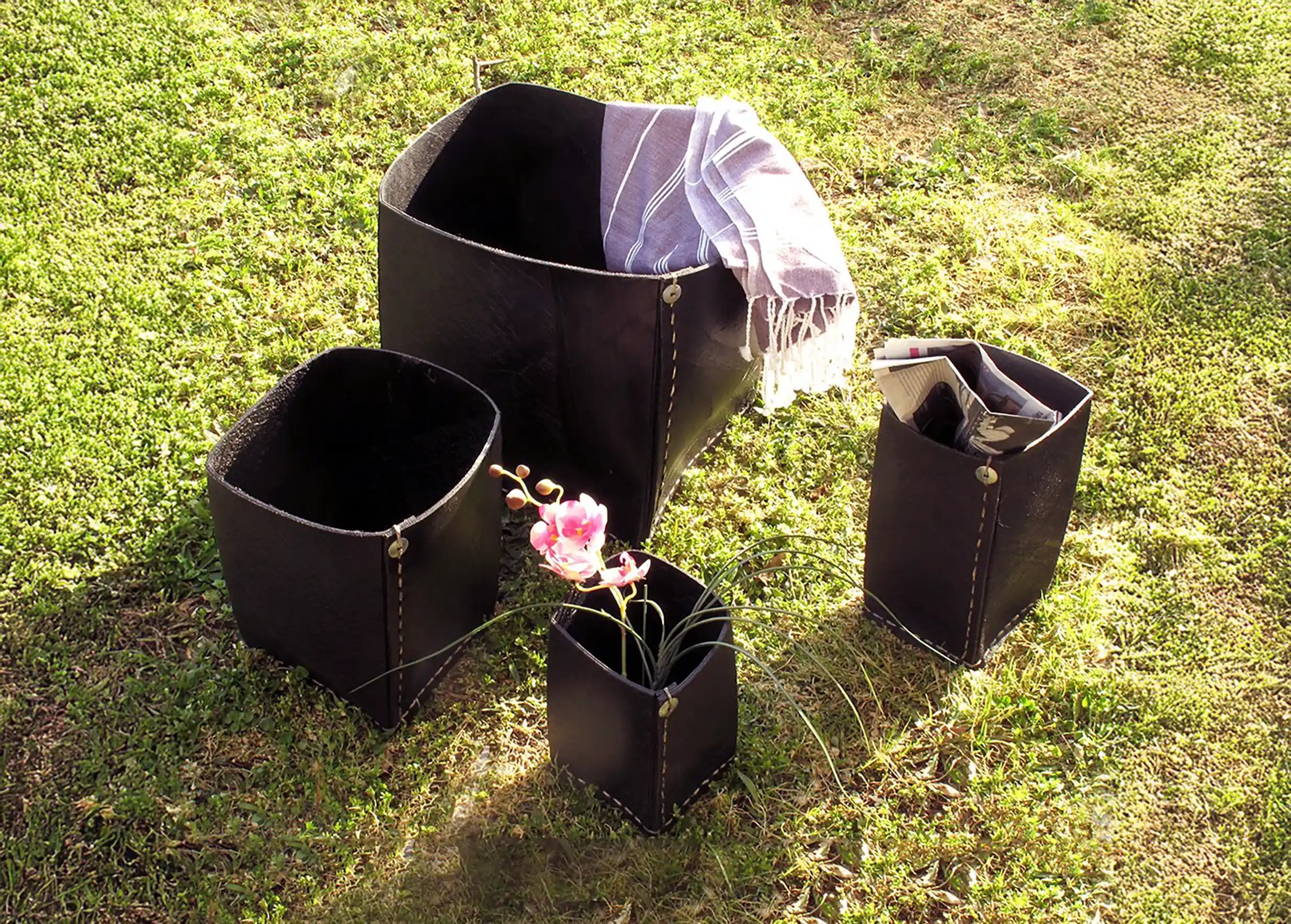 Large square planter in recycled tyres, placed on the grass with other models from the same collection.