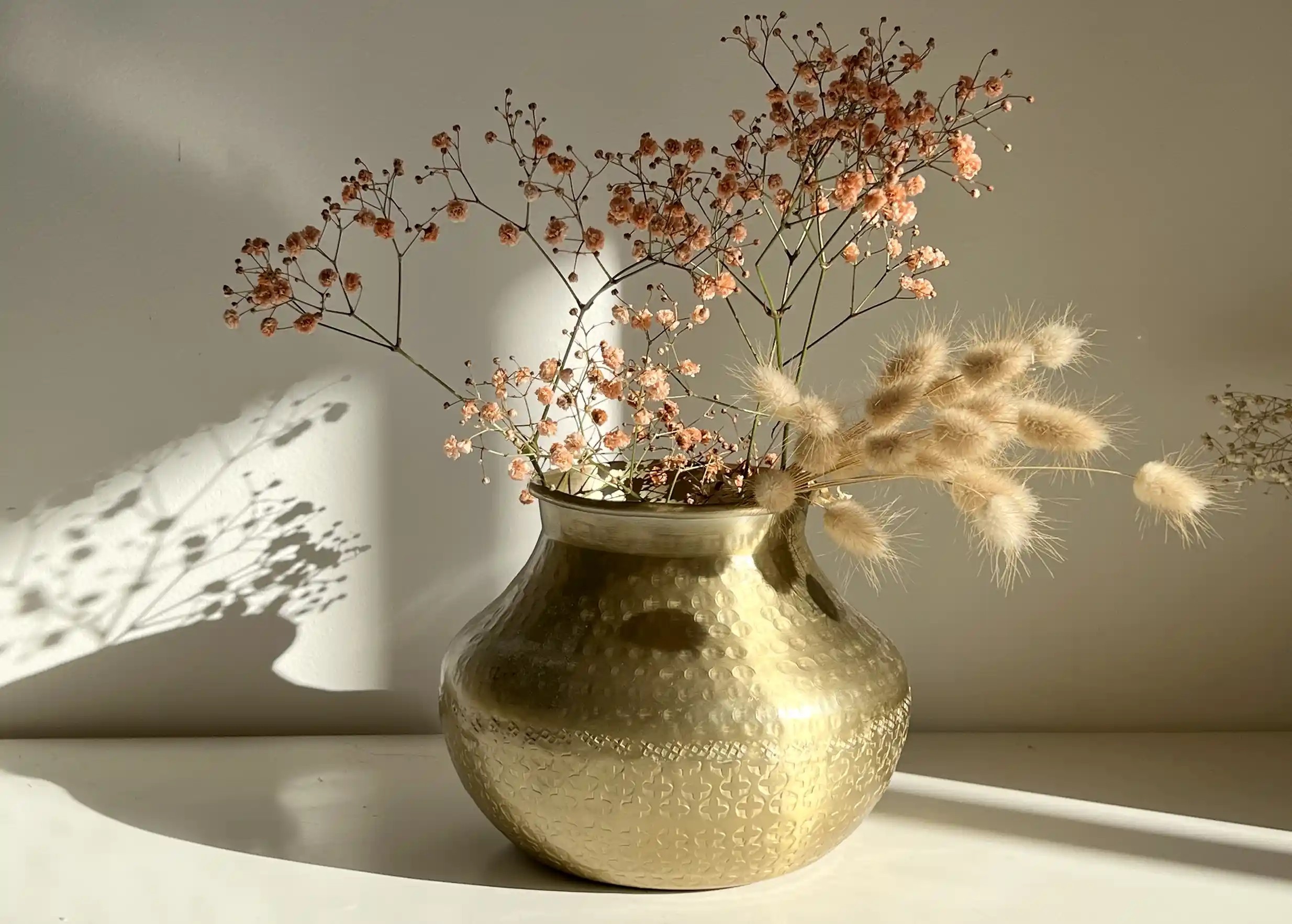 Vase déco en aluminium recyclé, contenant une composition de petites fleurs roses, espace lumineux
