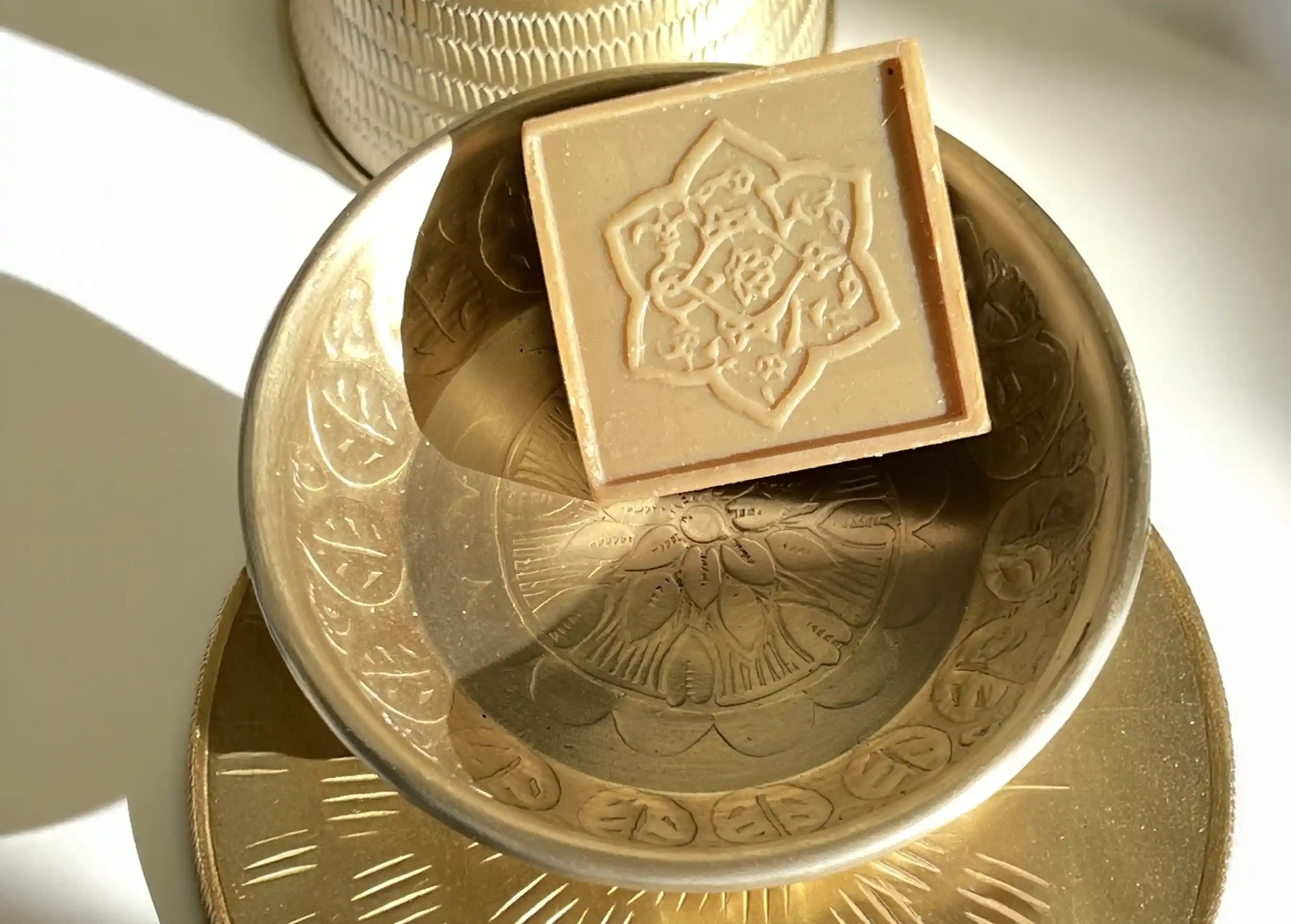 Gold-plated aluminium dish with engraved finish, containing a small Aleppo soap, by Karawan