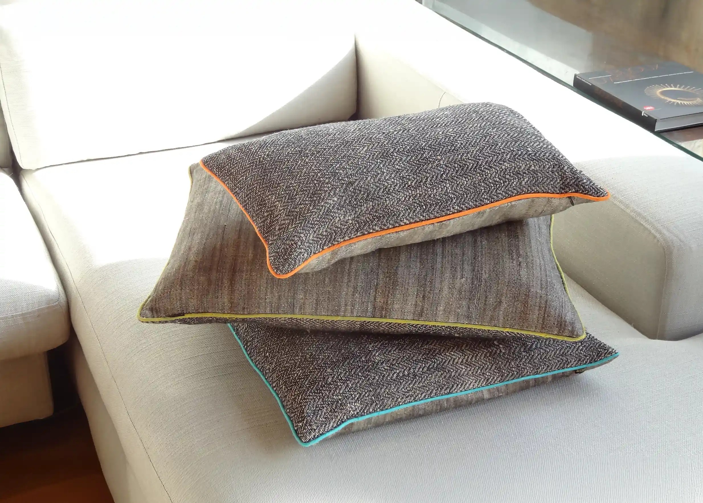 3 grands coussins rectangulaires en ortie et en soie, au passepoil coloré, posés les uns sur les autres