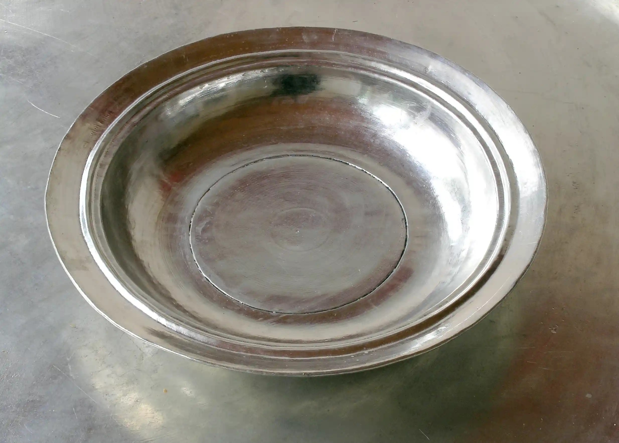 Assiette en cuivre étamé posée sur une table grise, création Karawan authentic